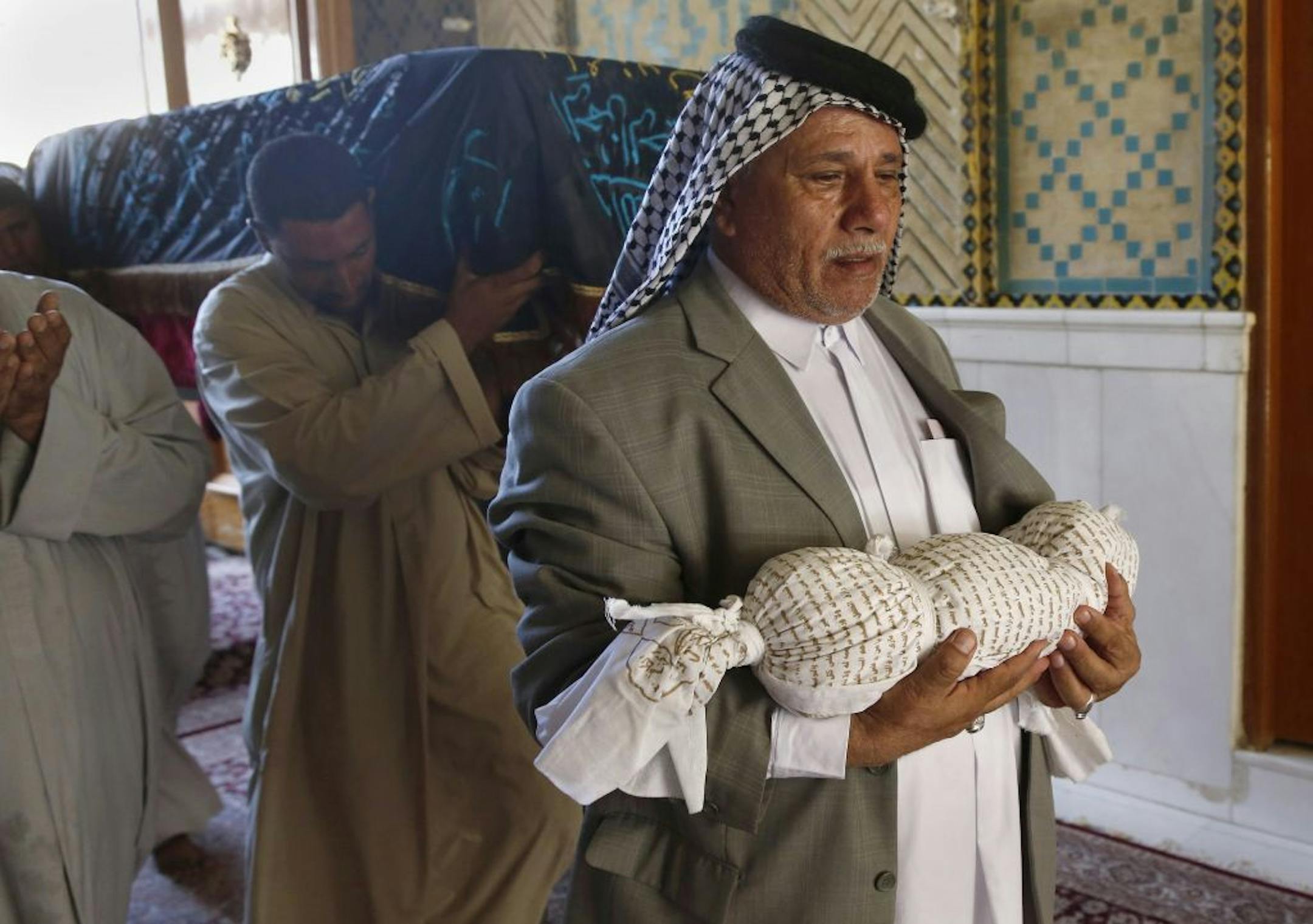 Mahmoud Abdel Rahman carries the body of his eleven-month old grandson, Latif, who was killed along with his mother on Monday when their house collapsed in a car bomb attack in Najaf, Iraq. Mourners carry the coffin of the mother, Hasnah Abdel Rasul, on Tuesday, Oct. 1.