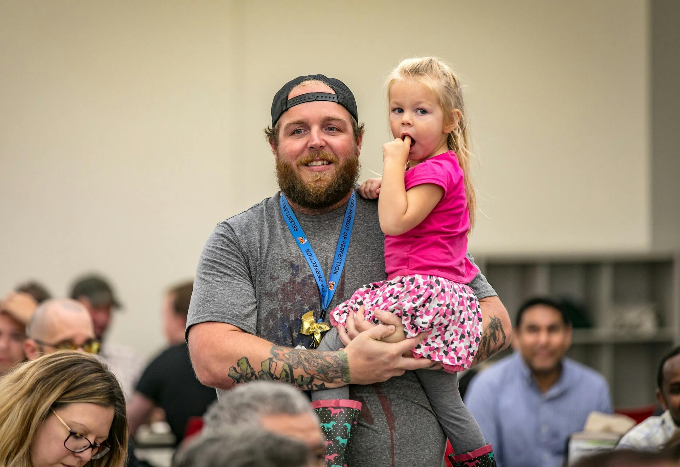 Michael Schoeneman holds his daughter, Oaklyn, at a graduation celebration at Amazon.com's fulfilment center in Shakopee, Minn., on Oct. 1, 2019, Schoeneman, a trainer, has worked at Amazon for two years. He earned a certification in welding. He was one of 88 employees in the first class to complete Amazon's Career Choice program, in which the company pays 95 percent of tuition for its workers to earn associate's degrees or professional certification for jobs inside or outside of Amazon.