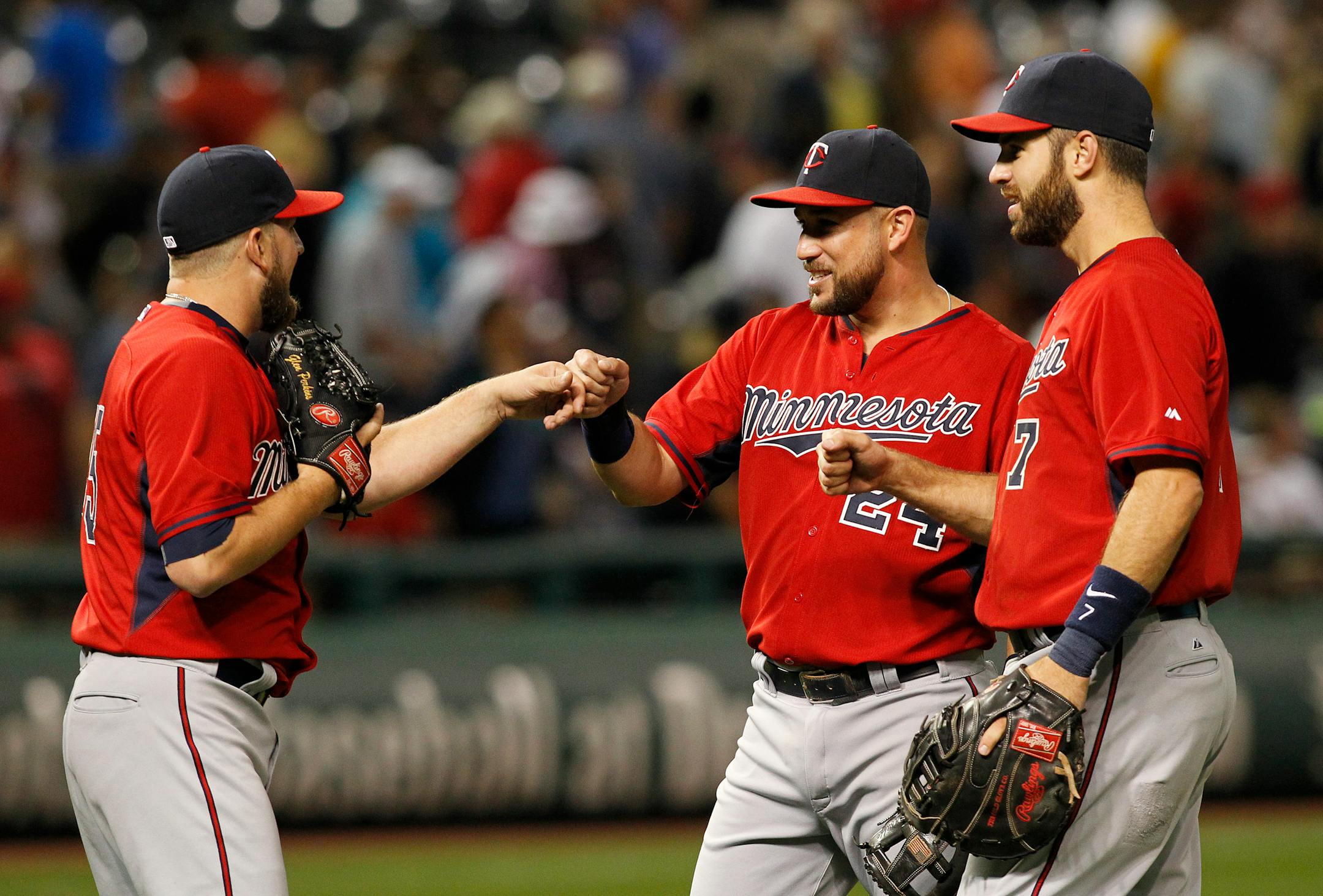 Minnesota Twins' Glen Perkins, left, is congratulated by teammates Trevor Plouffe, center, and Joe Mauer after defeating the Cleveland Indians 10-9 in a baseball game Friday, Aug. 7, 2015, in Cleveland. (AP Photo/Aaron Josefczyk