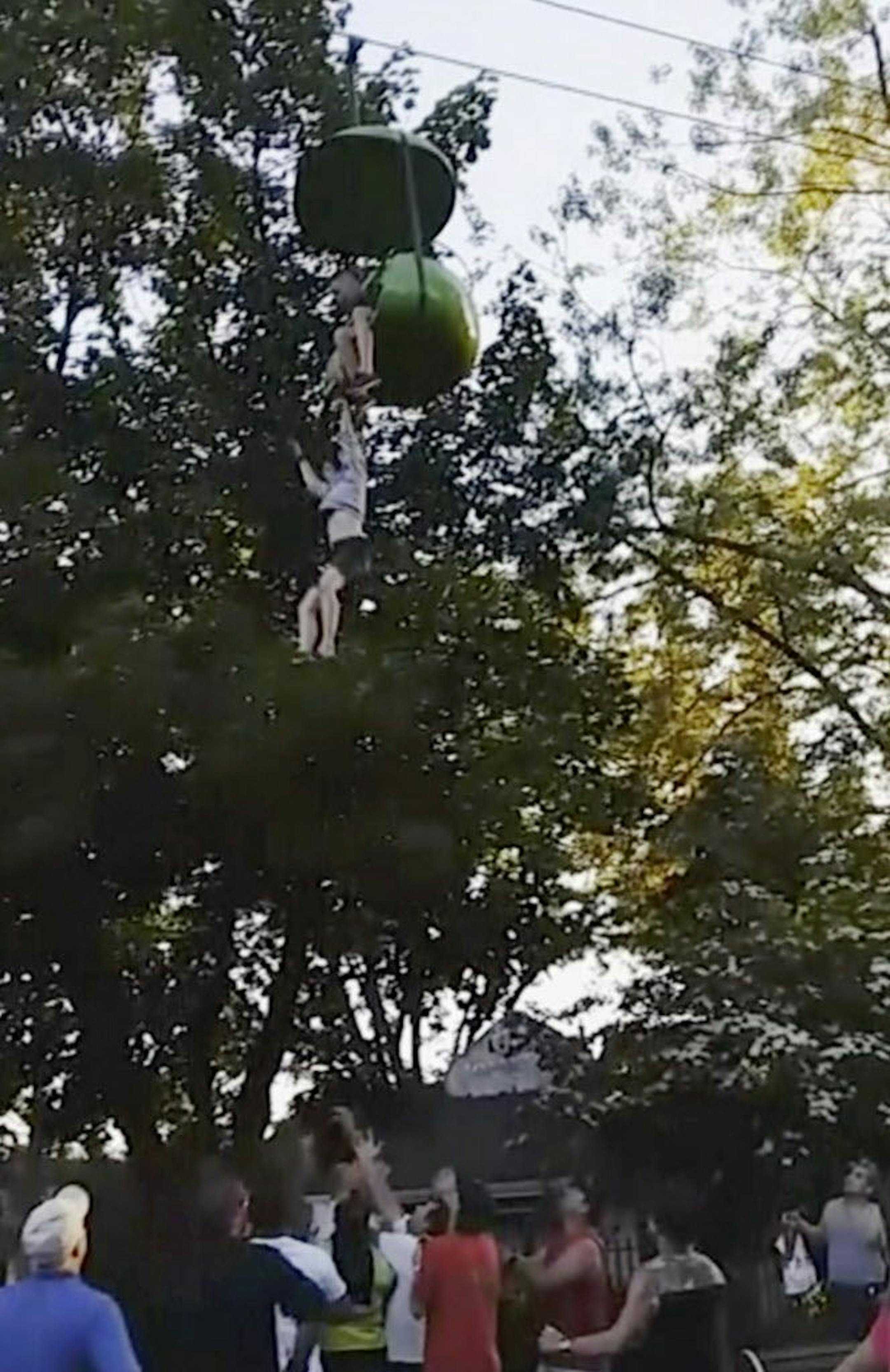 In this June 24, 2017, image made from a video provided by Leeann Winchell, a 14-year-old girl falls from an amusement park ride at Six Flags Great Escape Amusement Park in Queensbury, N.Y. After she lost her grip on the slow-moving gondola ride Saturday she fell into a crowd of park guests and employees gathered under the ride to catch her before she hit the ground. The teen, from Greenwood, Delaware, was taken to Albany Medical Center in stable condition with no serious injuries, the Warren Co