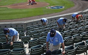 Ushers clean seats before a spring training baseball game between the Minnesota Twins and the Boston Red Sox in Fort Myers, Fla., Wednesday, March 2,