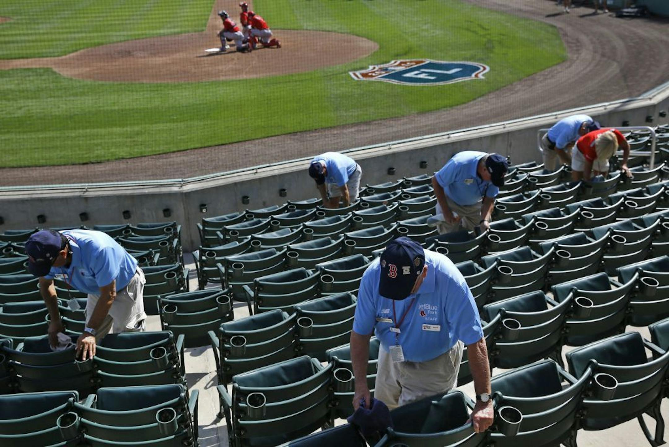 Ushers clean seats before a spring training baseball game between the Minnesota Twins and the Boston Red Sox in Fort Myers, Fla., Wednesday, March 2, 2016.