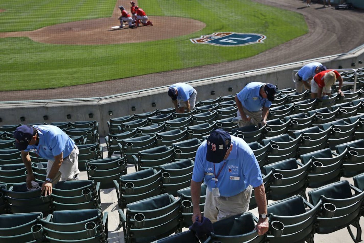 Ushers clean seats before a spring training baseball game between the Minnesota Twins and the Boston Red Sox in Fort Myers, Fla., Wednesday, March 2, 2016.