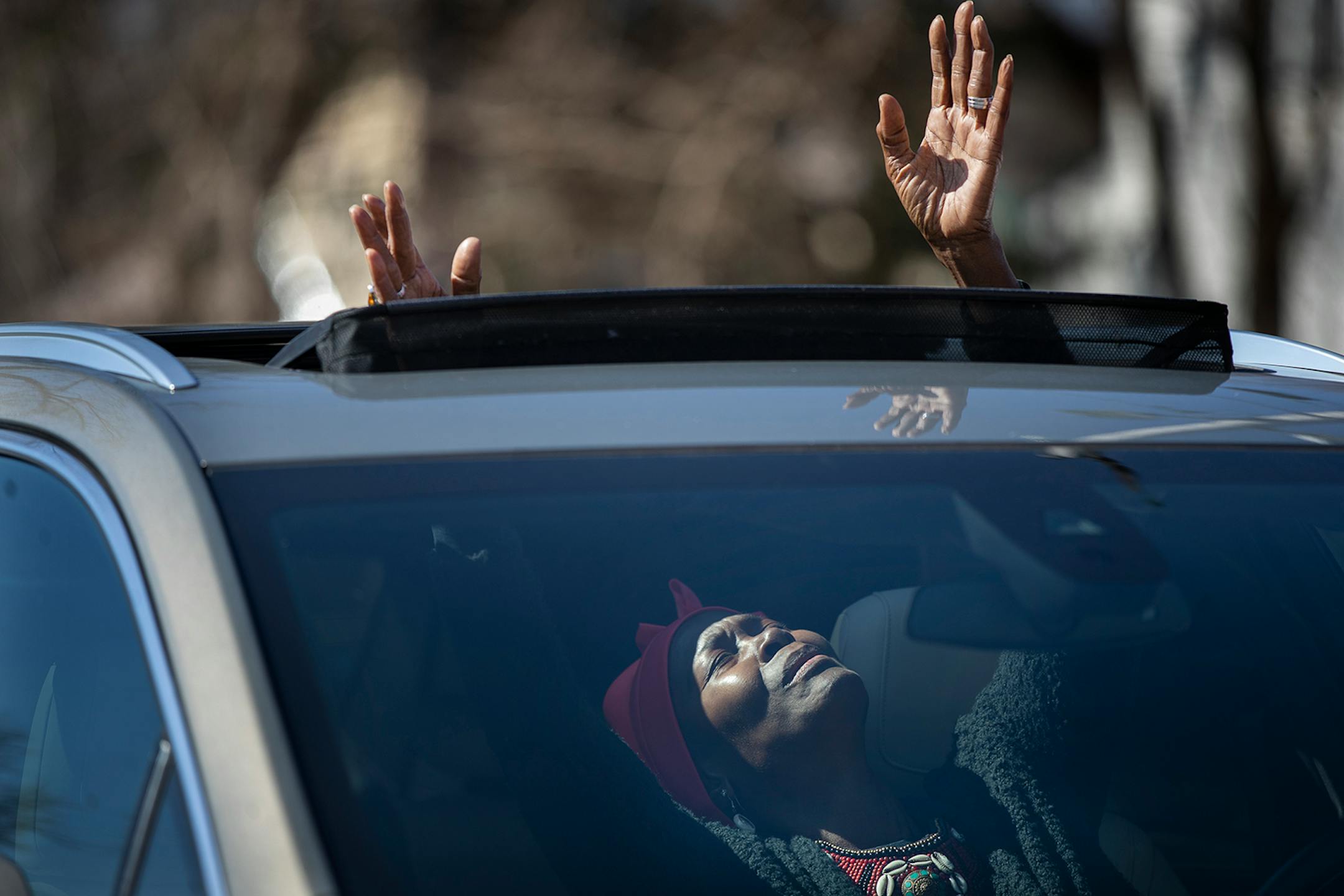 Peggie Hicks raised her hands in prayer through the sunroof of her car during "Park and Praise" service at New Hope Baptist Church.