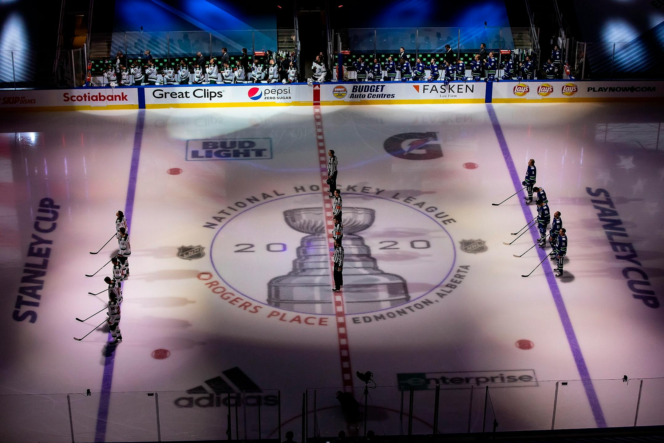 The Canucks and Wild stand for the national anthems before Game 1 of the series in Edmonton.