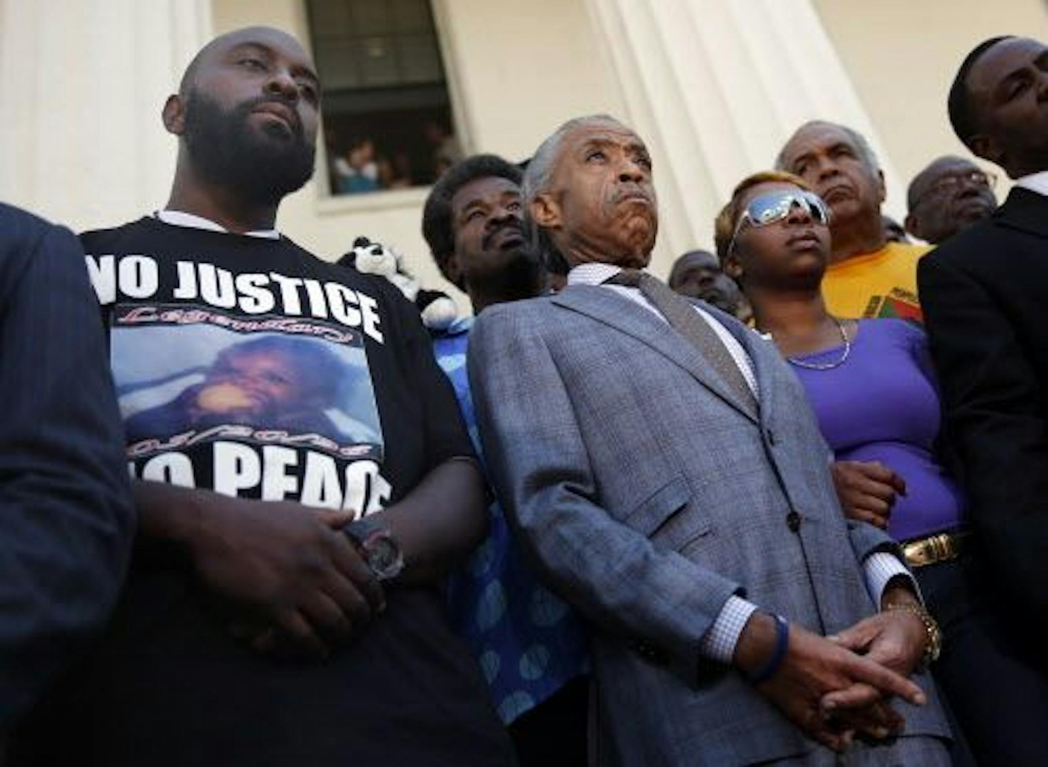 FILE - In this Aug. 12, 2014 file photo, civil rights leader Rev. Al Sharpton, center, stands with the parents of Michael Brown, Lesley McSpadden, right, and Michael Brown Sr., left, during a news conference outside the Old Courthouse in St. Louis.