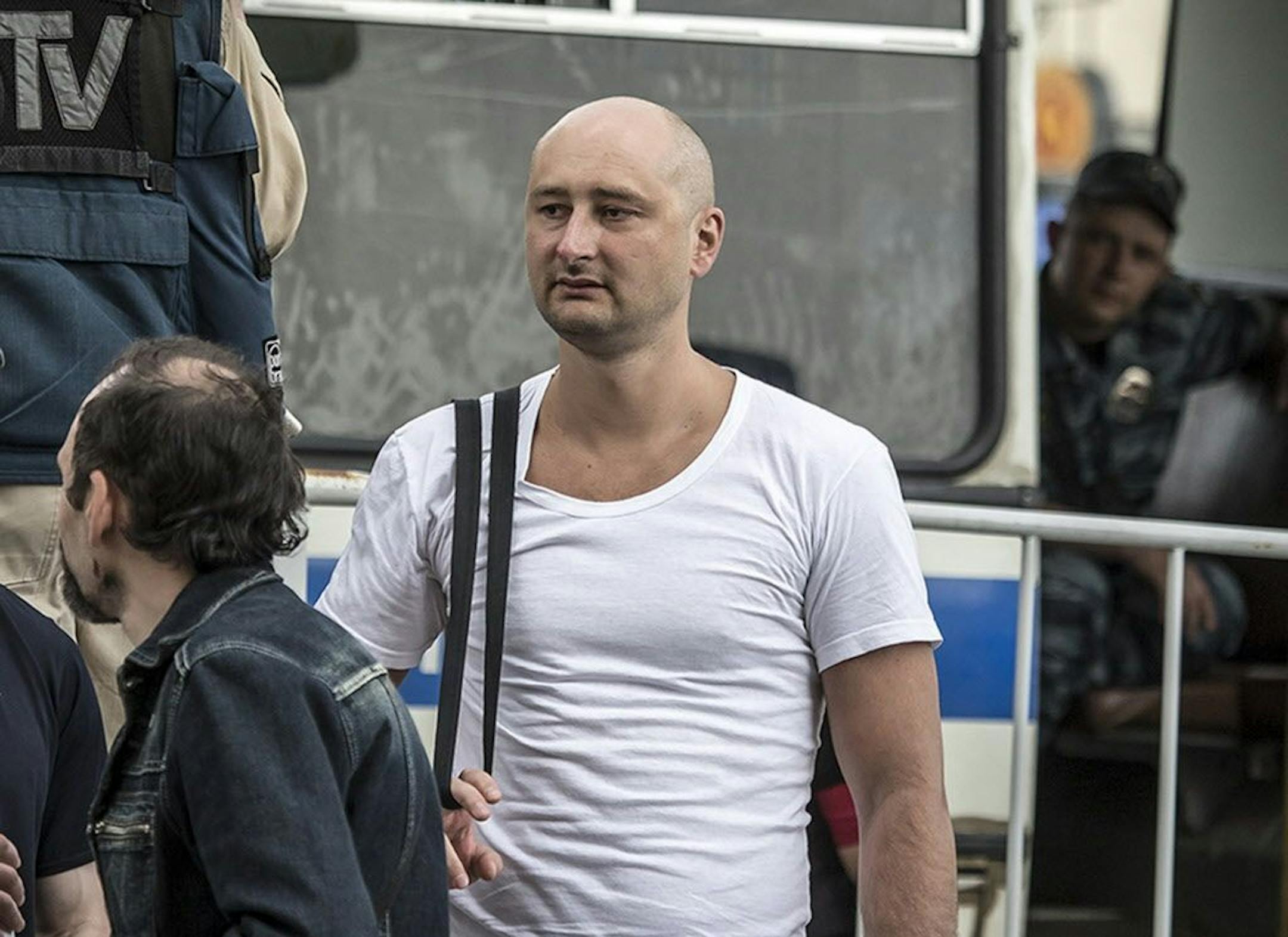 In this photo taken on Friday, May 31, 2013, Arkady Babchenko, 41, who had been scathingly critical of the Kremlin in recent years, stands at a police bus during an opposition rally in Moscow, Russia.