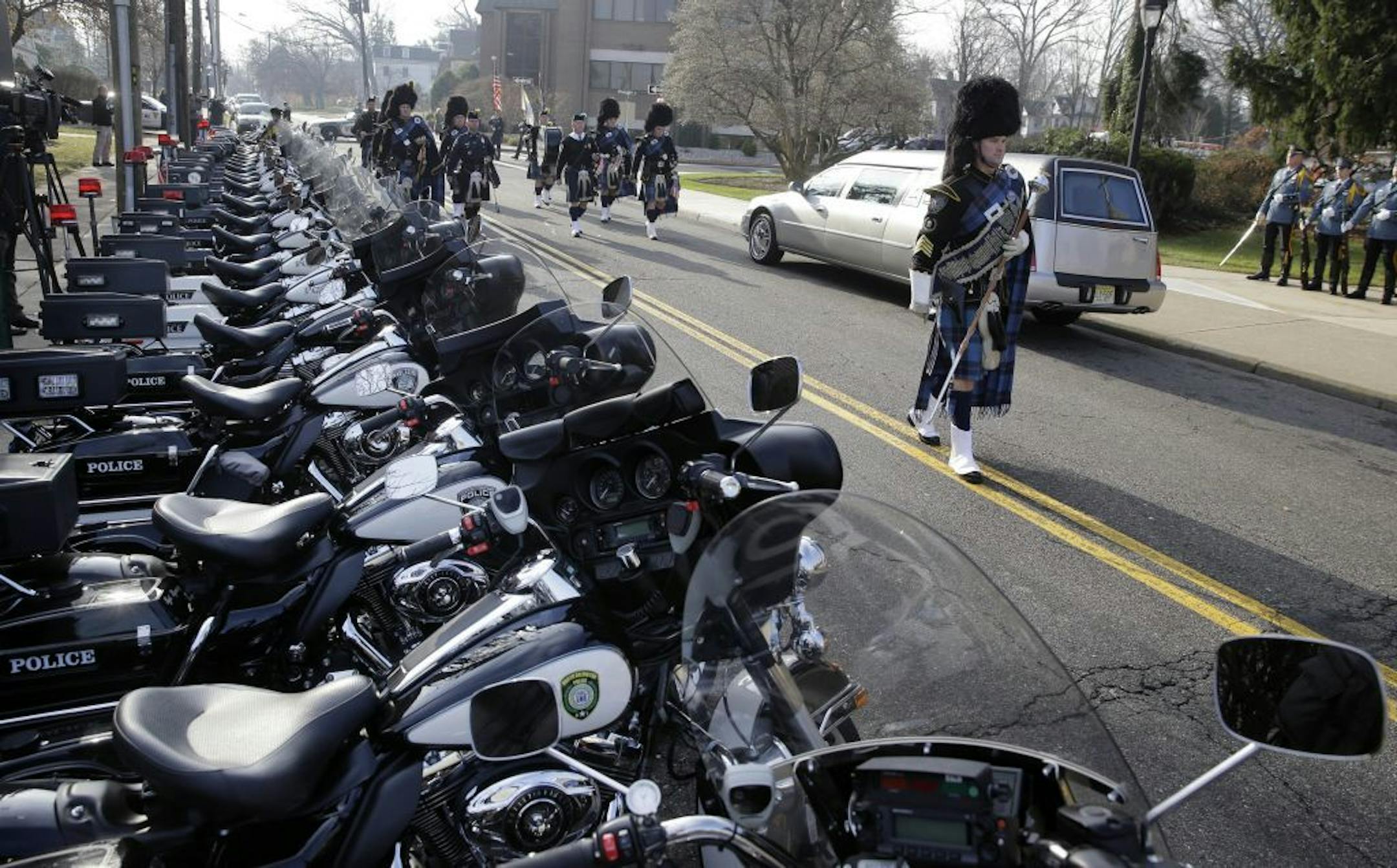 A pipe and drum band march past a row of police motorcycles during a procession for Michael Feeney, as Ridgewood, N.J., holds a funeral with full police honors for the 10-year-old boy, Tuesday, Dec. 3, 2013.