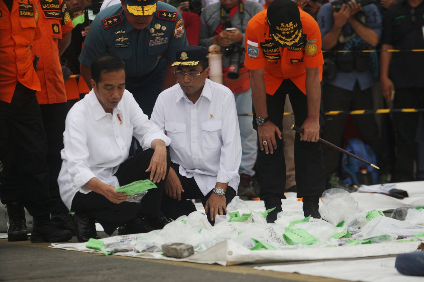 Indonesian President Joko Widodo, left, Transportation Minister Budi Karya Sumadi, center, and Chief of National Search and Rescue Agency Muhammad Syaugi, right, inspected debris and passengers' personal belongings retrieved from the waters where Lion Air flight JT 610 is believed to have crashed, during their visit at the rescuers command post at Tanjung Priok Port in Jakarta, Indonesia, Tuesday, Oct. 30, 2018. Relatives numbed by grief provided samples for DNA tests to help identify victims of