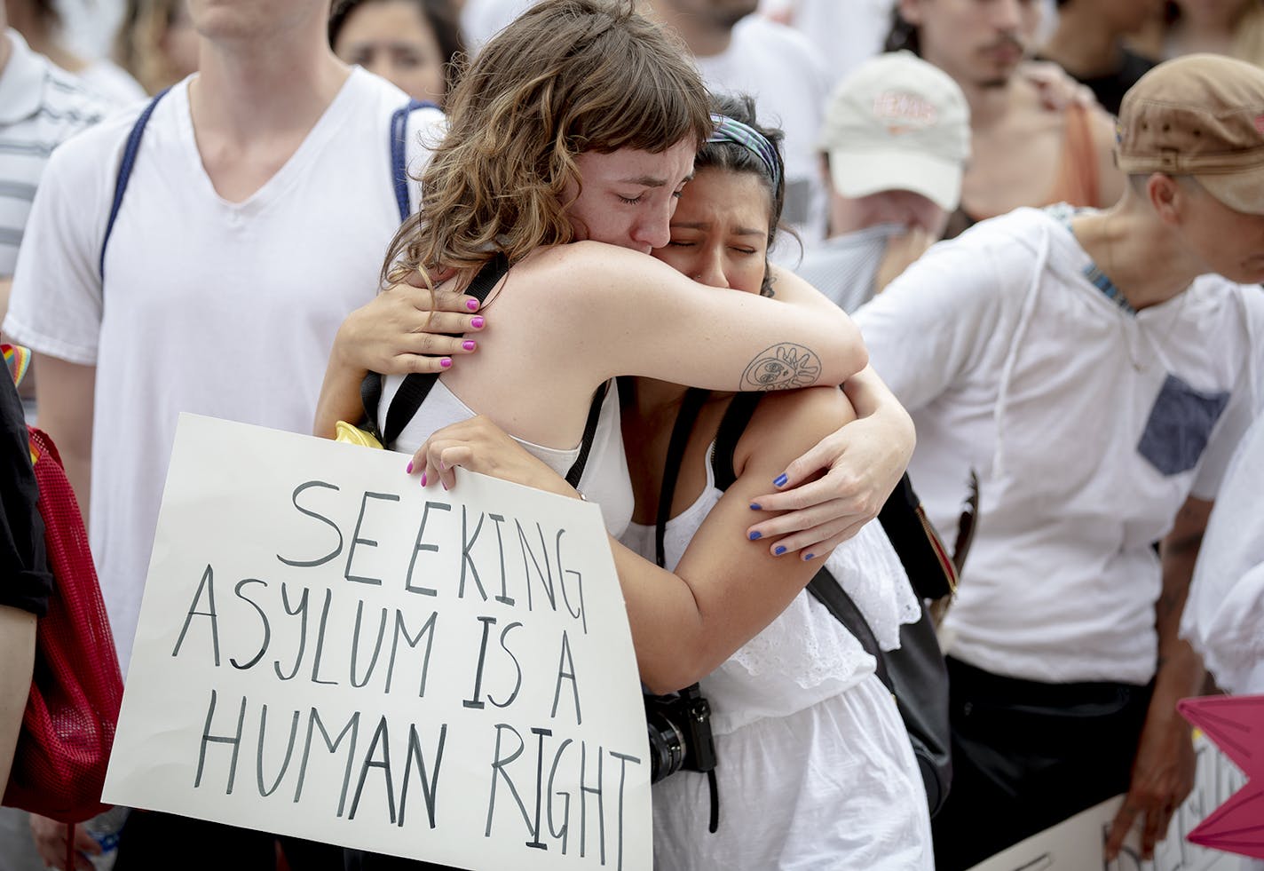 Karla Arias, right, comforts her friend, Katie Drackert, who became emotional during a moment of silence for the migrant children who have died at detention centers during a protest against detaining migrant children, Thursday, July 4, 2019, in Austin, Texas. (Nick Wagner/Austin American-Statesman via AP)