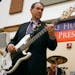 Republican presidential hopeful, former Arkansas Gov. Mike Huckabee plays a bass guitar with the band during a rally at the Mars Hill Academy Christia