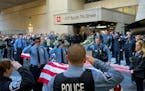Law enforcement officials saluted as their bodies of two slain officers and a medic were transported to the Hennepin County Medical Examiner's office 
