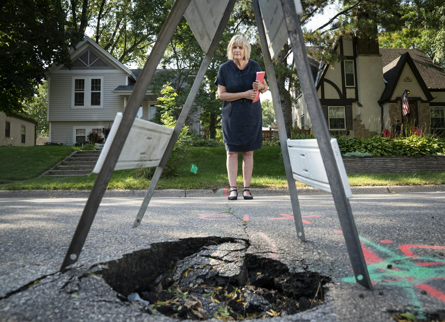 Amy Moeller found a sinkhole in front of her house this summer. The underlying sewer pipe problem below ground will cost her and her neighbor $31,000 to repair. This is likely due to the high water table also impacting other homes in neighborhoods near Lake Nokomis in Minneapolis, Minn., on Tuesday, September 17, 2019. She is holding a file full of paperwork she has been going through to solve this problem. ] RENEE JONES SCHNEIDER &#xa5; renee.jones@startribune.com