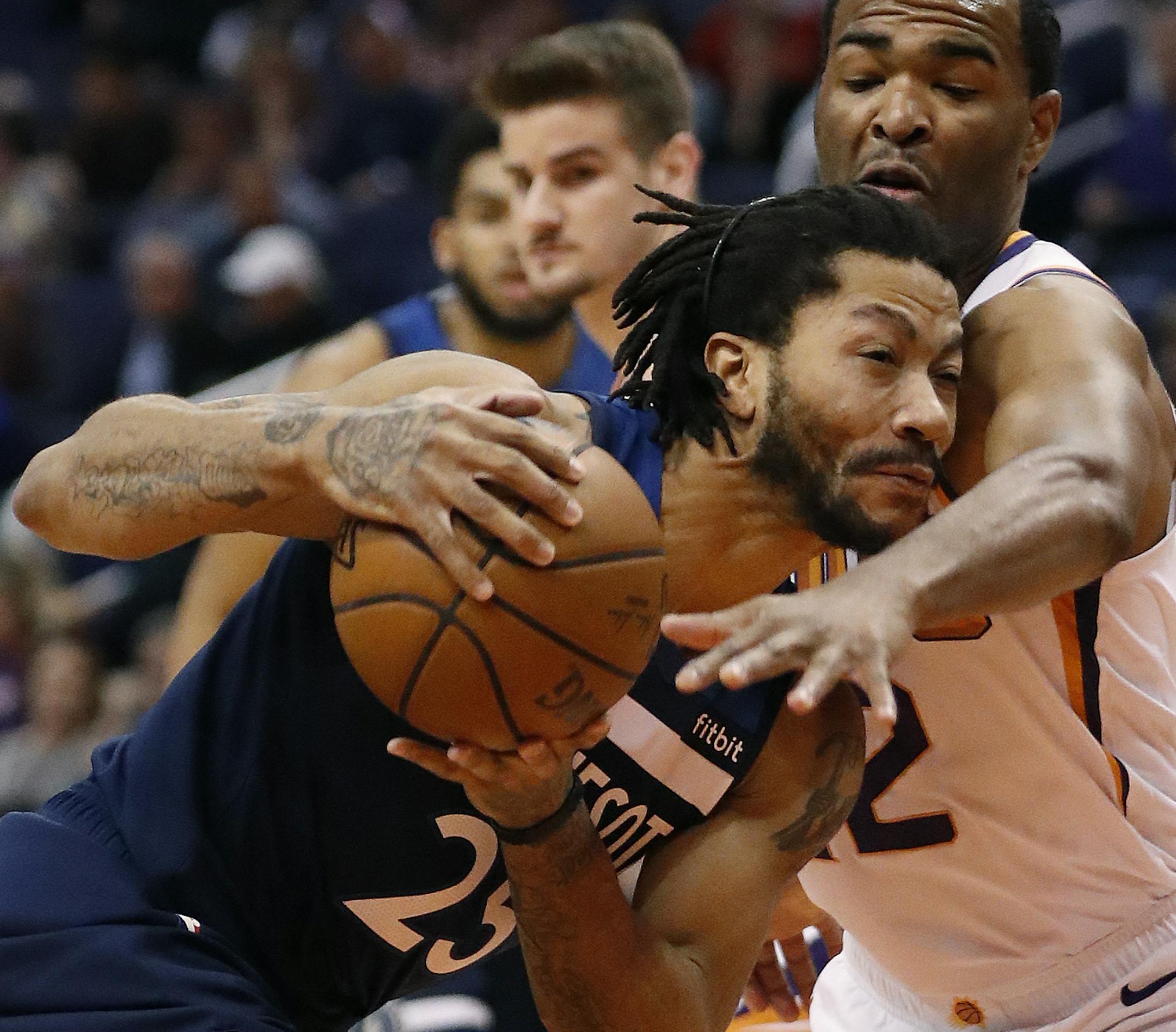 Minnesota Timberwolves guard Derrick Rose (25) tries to slip past Phoenix Suns forward T.J. Warren, right, during the first half of an NBA basketball game, Tuesday, Jan. 22, 2019, in Phoenix. (AP Photo/Matt York)