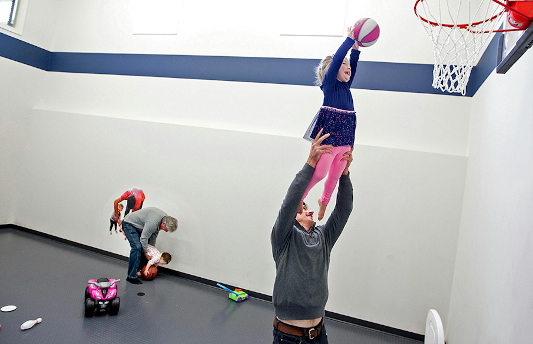 Minnesota Wild's Ryan Carter, right, holds his daughter Maggie, 3, up for a basket while his dad, Mike Carter, holds onto Ryan's younger daughter Natalie, 15 months, at Ryan's home in Gem Lake November 22, 2015.