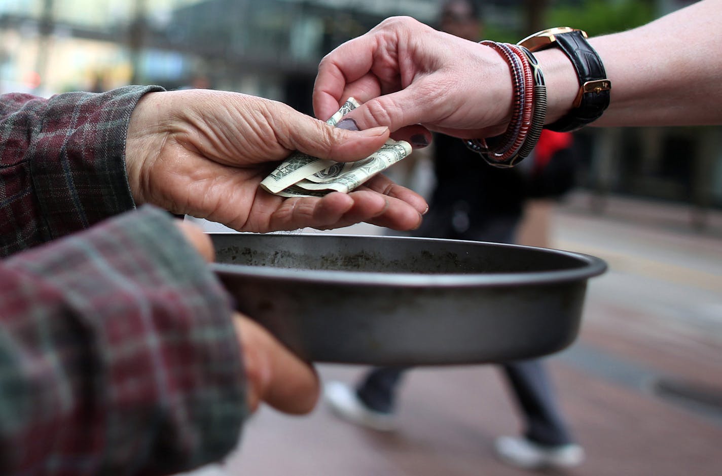 Edwin Schall got a dollar from a passerby as he held out a pan t get money for food along Nicollet Ave. ] (KYNDELL HARKNESS/STAR TRIBUNE) kyndell.harkness@startribune.com In downtown Minneapolis, Min. Tuesday, June 3, 2014. A new campaign in Minneapolis wants to end panhandling. The "Give Real Change Campaign" which has billboards in Downtown Minneapolis, is telling residents to end panhandling and give to a charitable organization instead. ORG XMIT: MIN1406031618130714 ORG XMIT: MIN140610104739