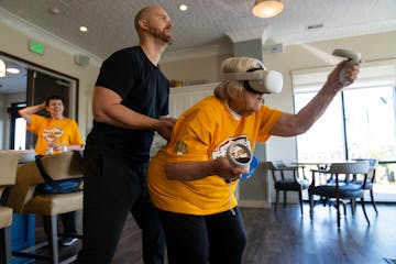 Carole Johnson, a resident of the Pillars of Prospect Park, tries out virtual reality tennis with personal trainer Ian Williams of FitVive.