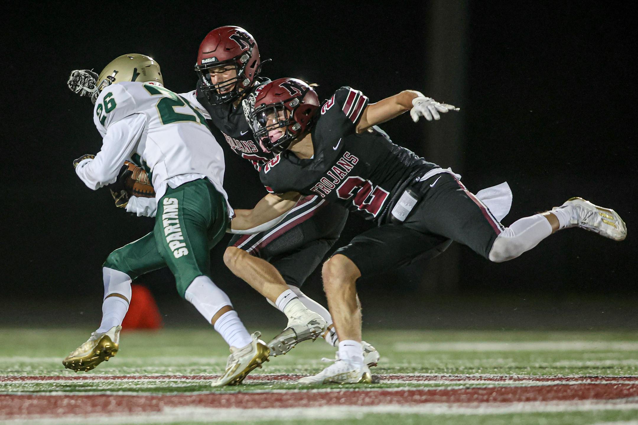 New Prague defenders Jake Hemann (2) and Will Seymour stretch to stop Rochester Mayo running back Isaiah Beale late in the second quarter. Mayo led 21-7 at the half. Photo by Mark Hvidsten, SportsEngine