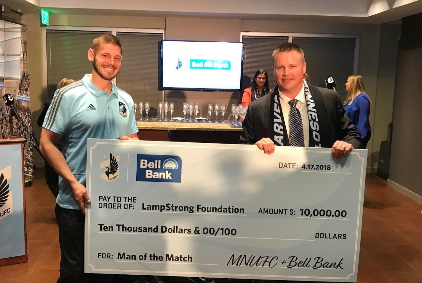 Minnesota United goalkeeper Matt Lampson (left) received a $10,000 check on behalf of his foundation from Bell Bank President Michael Solberg.