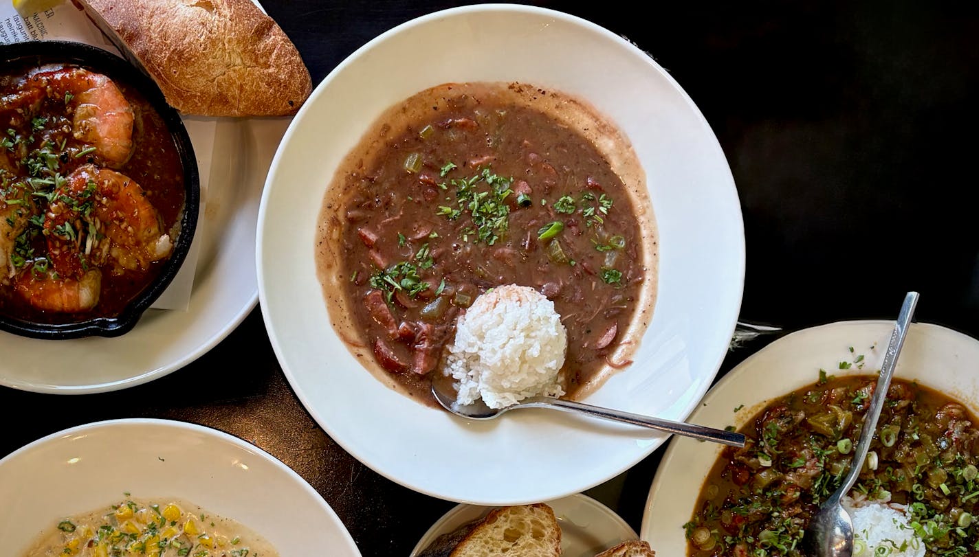 A table filled with food with a bowl of red beans and a scoop of white rice in the center.