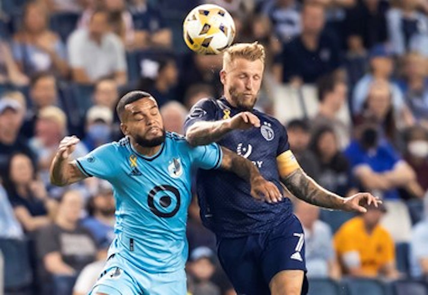 Sporting Kansas City forward Johnny Russell (7) goes up for a head ball against Minnesota United defender D.J. Taylor (26) during an MLS soccer match Wednesday, Sept. 15, 2021, in Kansas City, Kan. (Nick Tre. Smith/The Kansas City Star via AP)