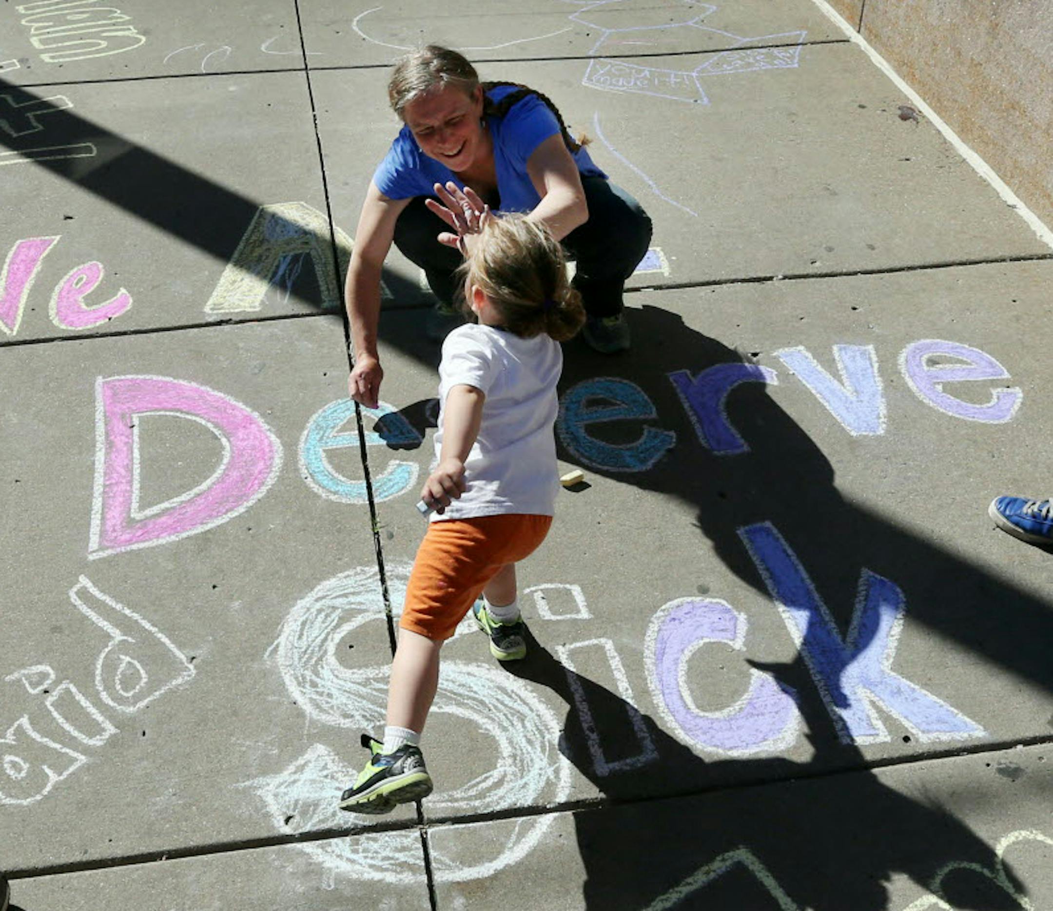 Camilo Segovia 3, high-fived his mother, Kristen Melby, as they drew with chalk on the sidewalk in front of Minneapolis City Hall on Wednesday. The Minneapolis City Council was holding a final public hearing on the proposed sick-leave ordinance.