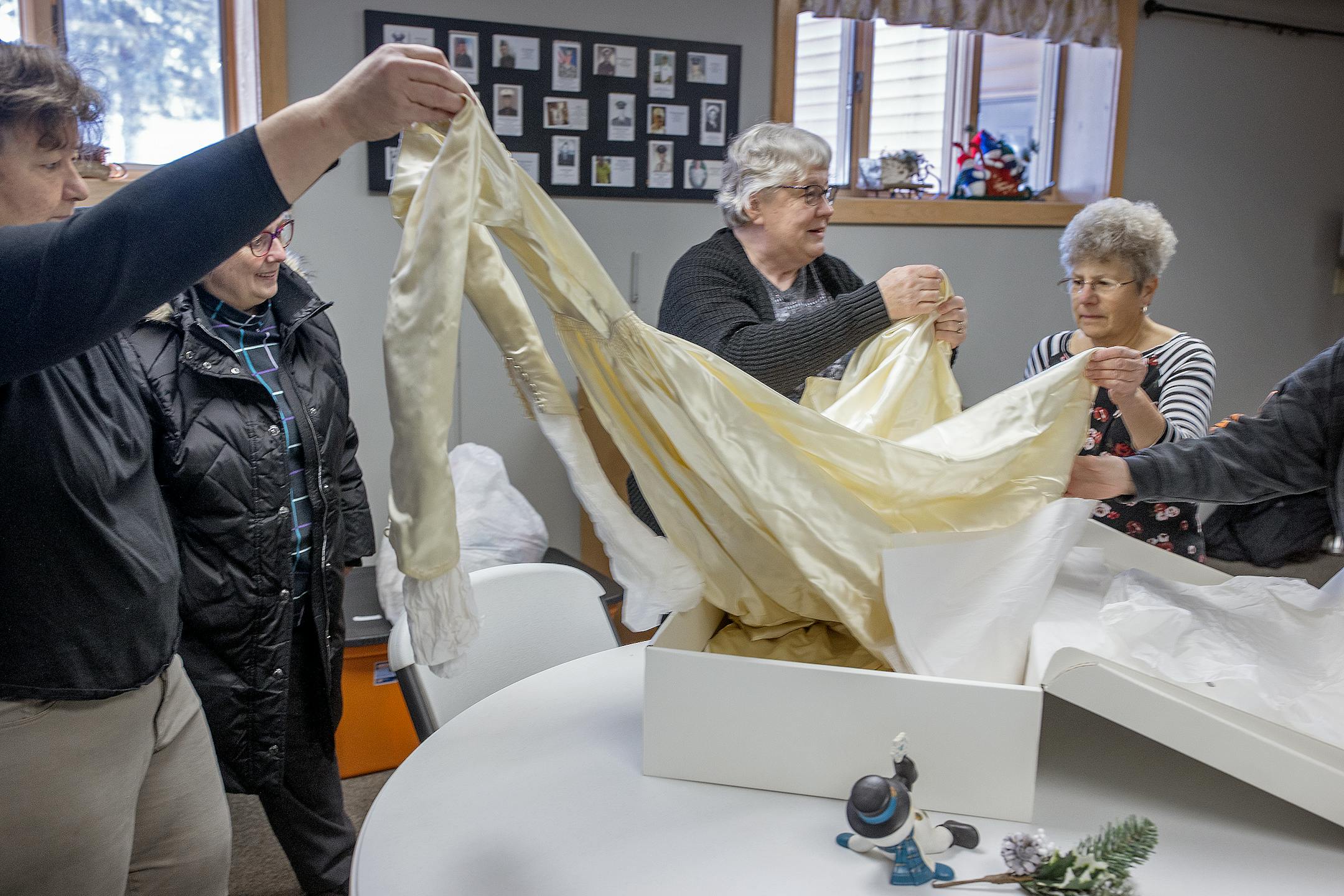 Patty Hauer, center, and her church group take out a used wedding dress that was donated for their cause as they work in the All Saints Lutheran Church basement in  Darwin, Minn.  The group of volunteers take donated wedding and prom dresses and turn them into "Angel Dresses" used for burial outfits for infants and newborns who die. Often the bereaved families of these babies don't have anything to bury their child in, and the dress program fills that need.