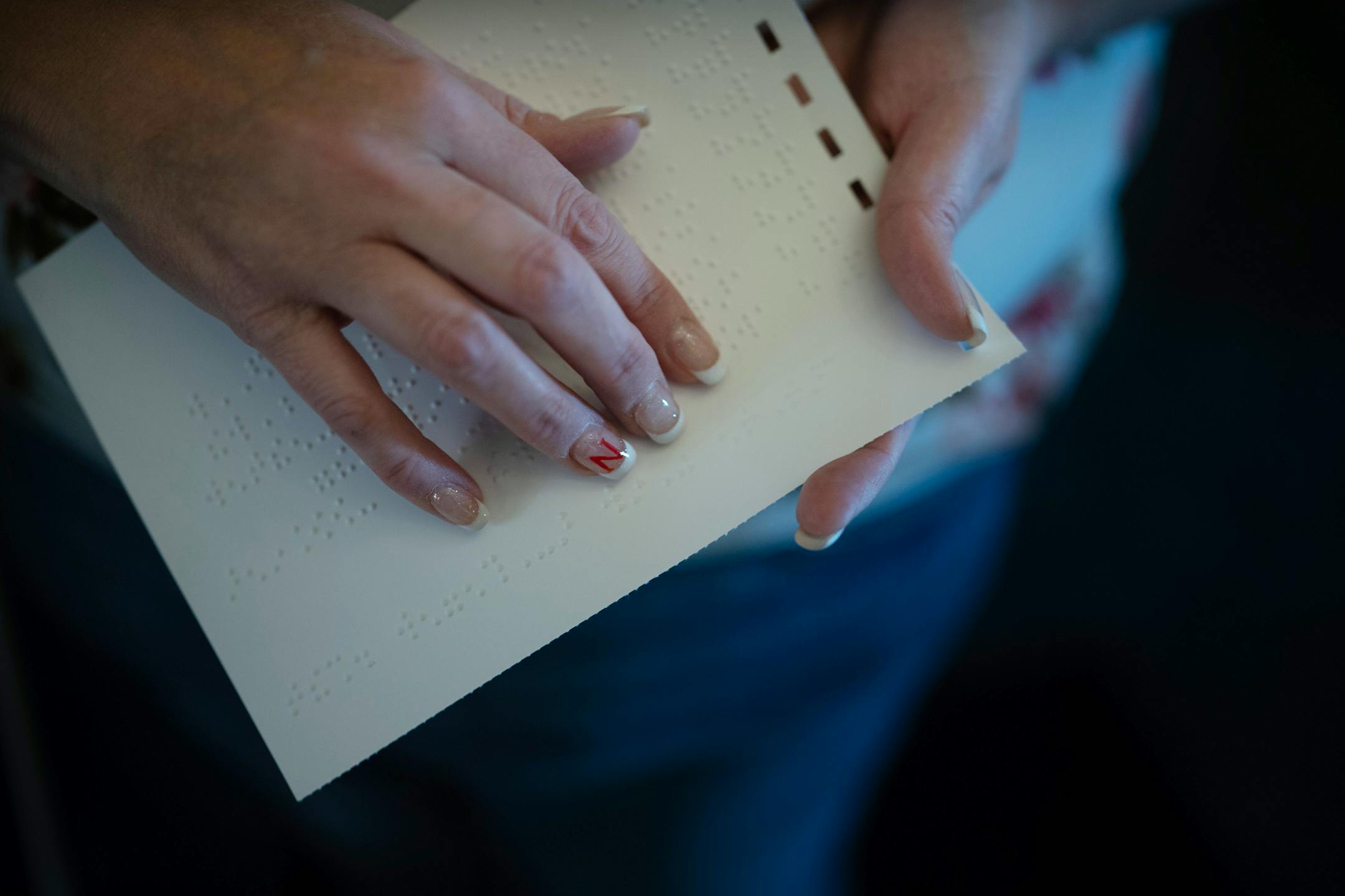 Harley Acy, a home management instructor at BLIND, Inc. reads braille for instructions on a scavenger hunt.