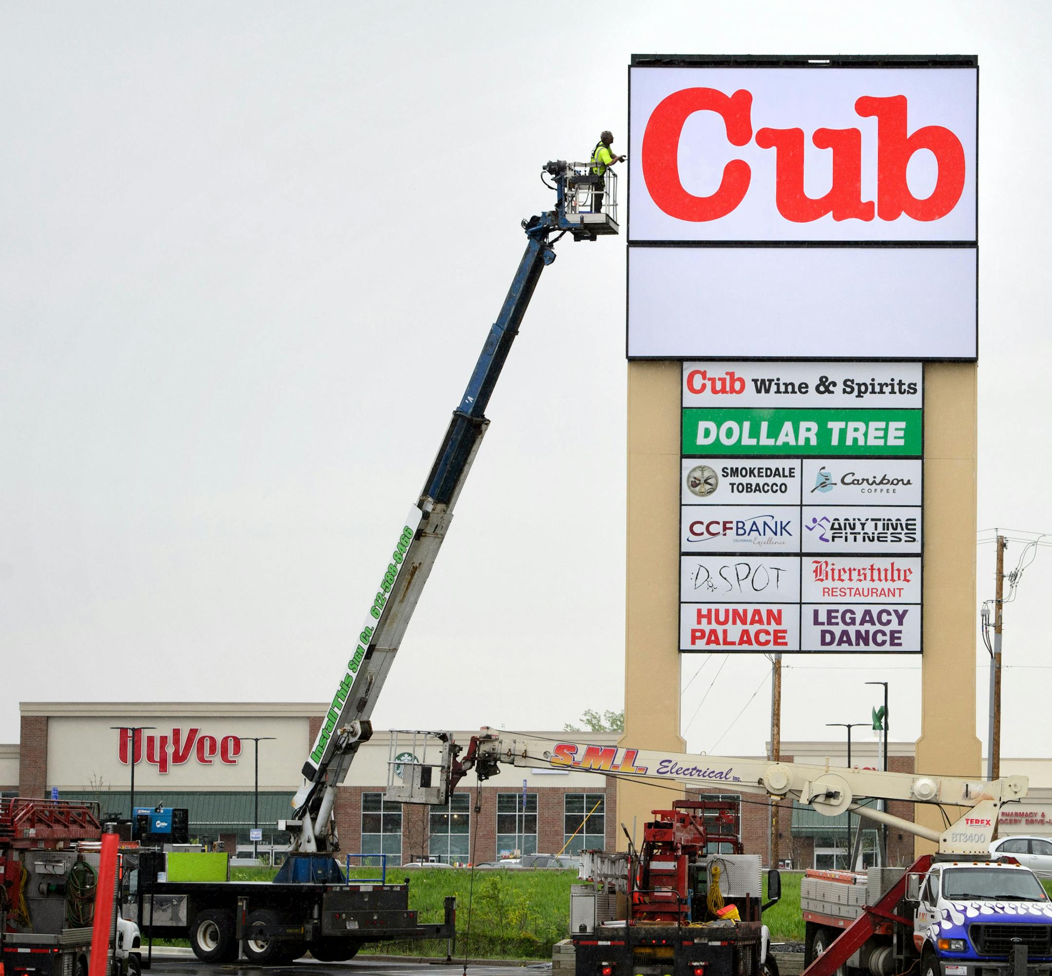 A worker puts finishing touches on the Cub Foods sign directly across the street from Hy-Vee in Oakdale.