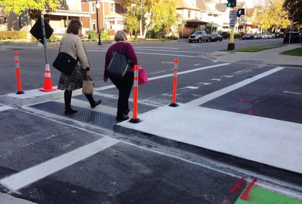 Two women crossed E. 28th Street at Chicago Avenue S. through a pedestrian median designed to make it easier for people to cross 28th.