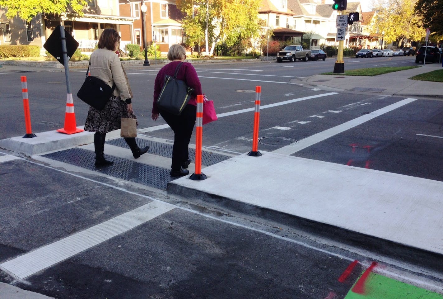 Two women crossed E. 28th Street at Chicago Avenue S. through a pedestrian median designed to make it easier for people to cross 28th.