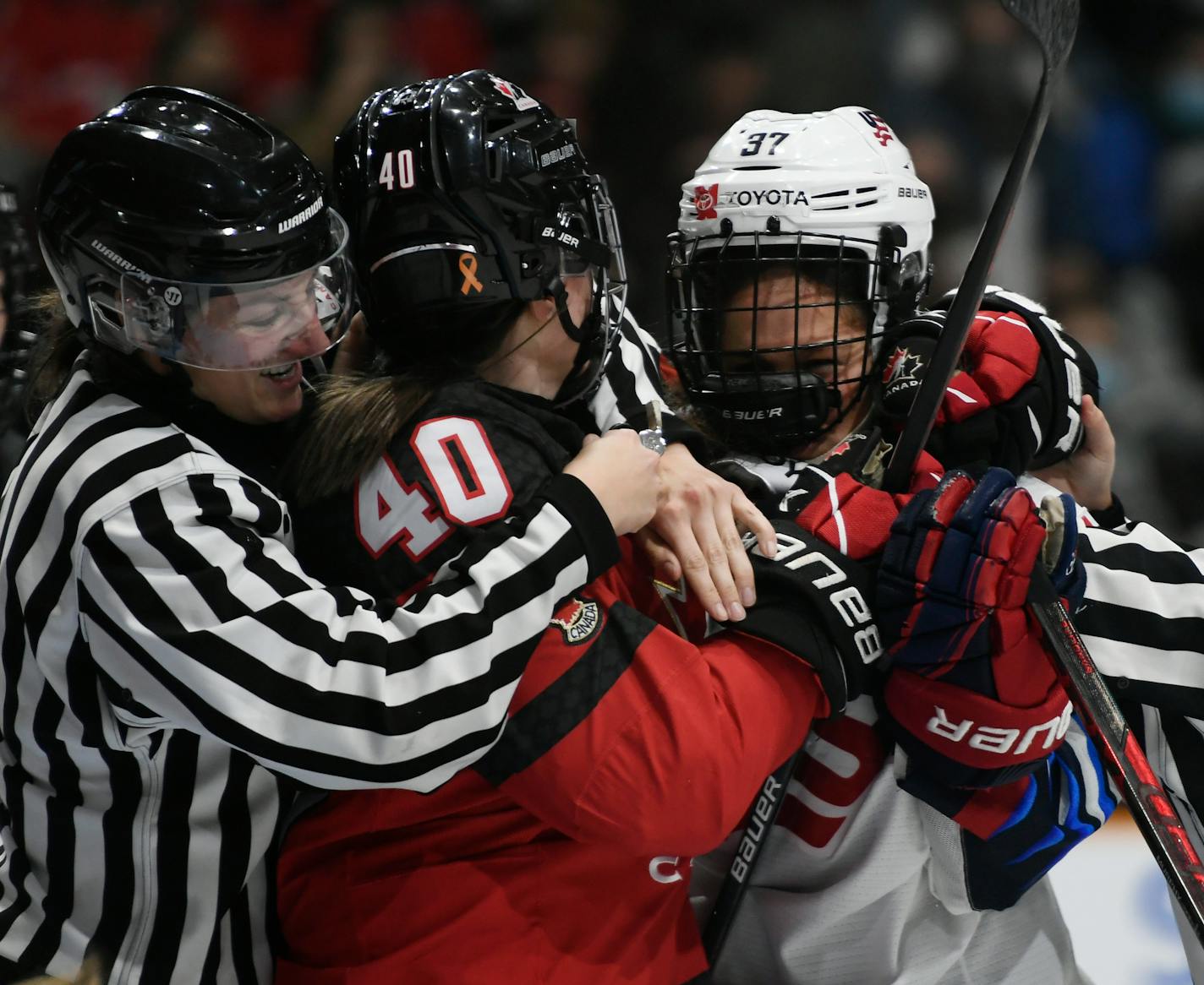 Officials get their arms around Canada's Blayre Turnbull (40) and United States' Abbey Murphy (37) during a shoving match in the first period of a hockey game in Ottawa, Ontario, Tuesday, Nov. 23, 2021. (Justin Tang/The Canadian Press via AP)