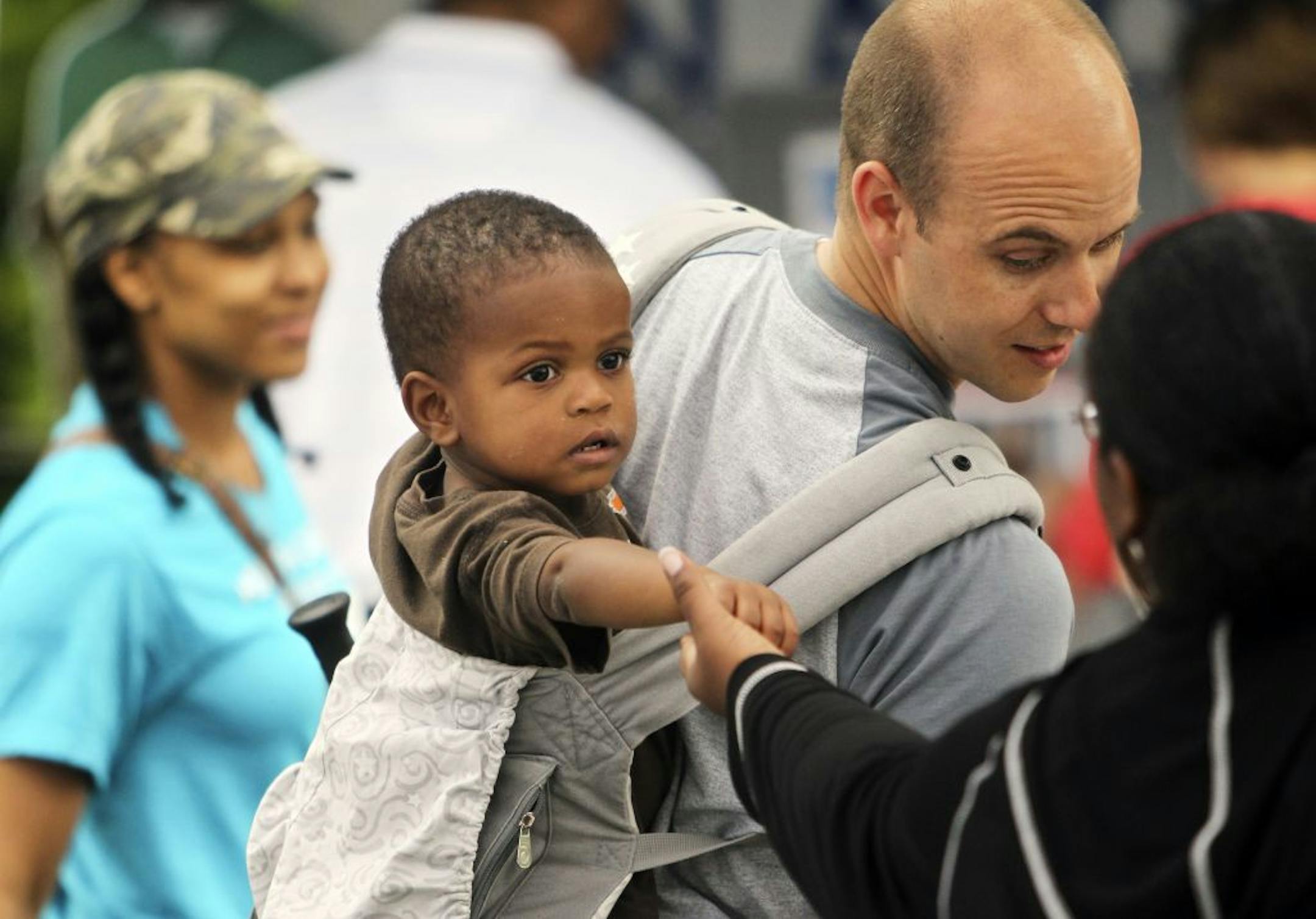 Carver Buse, 20 months, rides in a backpack on the back of his dad Nick Buse of New Brighton, as Carver showed off a temporary tattoo to Victoria Balko, right, who was working the City of Lakes Community Land Trust booth at North Mississippi Regional Park Saturday, June 16, 2012, in Minneapolisl, MN. Father and son and mom Traci and big sister Samantha, 5, not pictured, were all taking in Juneteenth festivities.