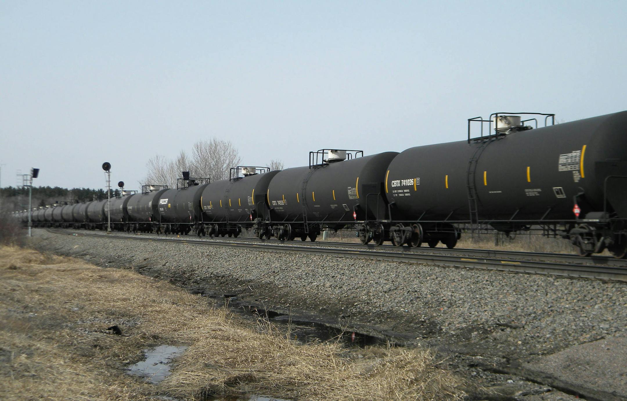 FILE - In this April 15, 2014 file photo, an oil-tank train with crude oil from the Bakken shale fields of North Dakota travels near Staples, Minn. The University of Minnesota releases a new study on financial losses for farmers due to rail delays in shipping agriculture commodities, blaming the vast quantities of oil leaving North Dakota for squeezing out other rail traffic. (AP Photo/Mike Cronin,File)
