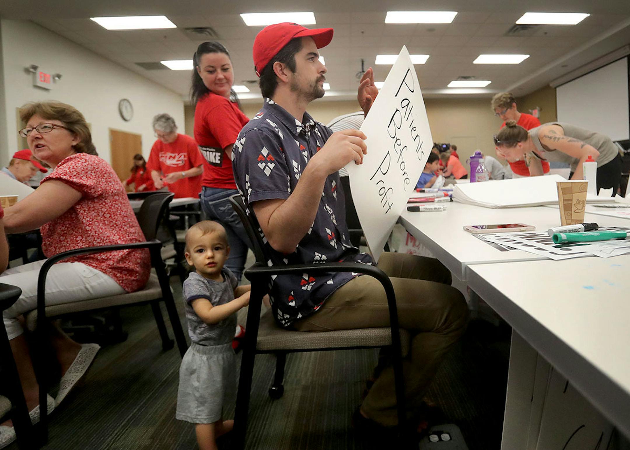 ]Ezra Hicks, 11 months, watches as his dad Jack Hicks make a sign as they joined MNA nurses, Minnesota Nurses Association employees and family members at the MNA headquarters to make posters for picketing Saturday, June 18, 2016, should a strike happen Sunday at five Twin Cities Allina Health facilities Ezra's mom Christine Hicks is an RN at United Hospital in St. Paul.