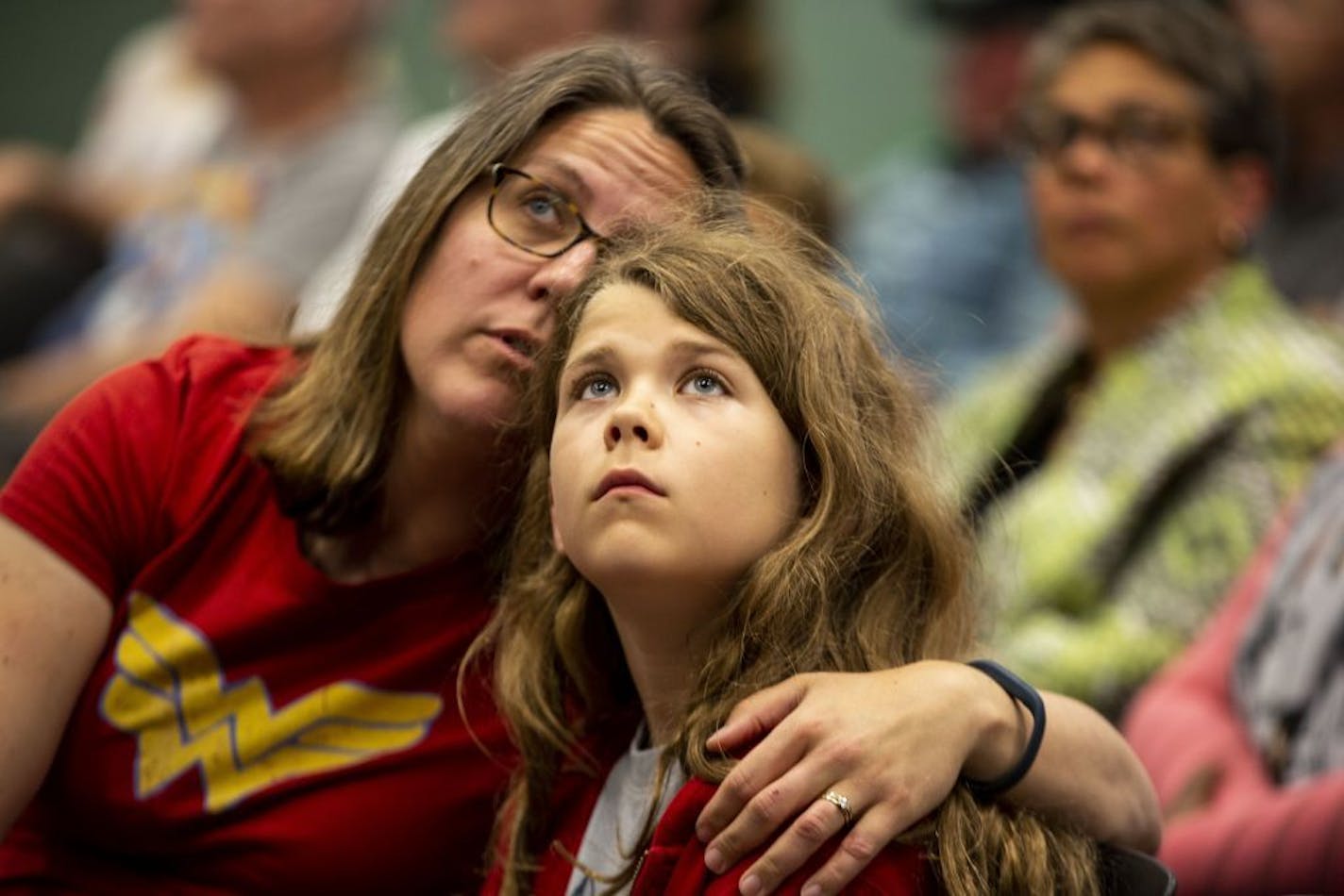 Marianne Milligan talks to her son, Jack Milligan-Wells, 10, during board meeting discussions. They were wearing red in support of the proposed renaming of Linwood Monroe Arts Plus to Global Arts Plus.