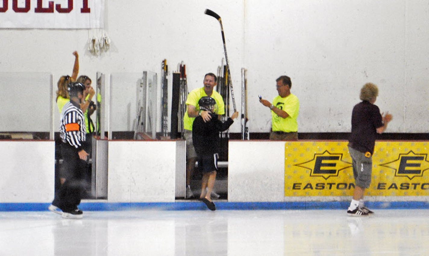 Nate Smith, 11, holds his stick up in jubilation after sinking a trick shot during a charity hockey game Aug. 11, 2011, in Faribault, Minn.