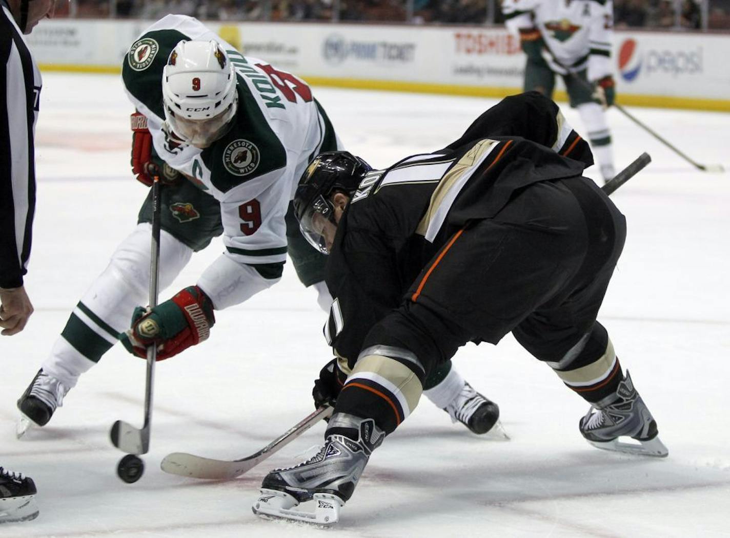 Minnesota Wild center Mikko Koivu (9), of Finland battles his brother, former Anaheim Ducks center Saku Koivu (11), of Finland on a face off in the first period of an NHL hockey game Wednesday, Dec. 11, 2013 in Anaheim, Calif.