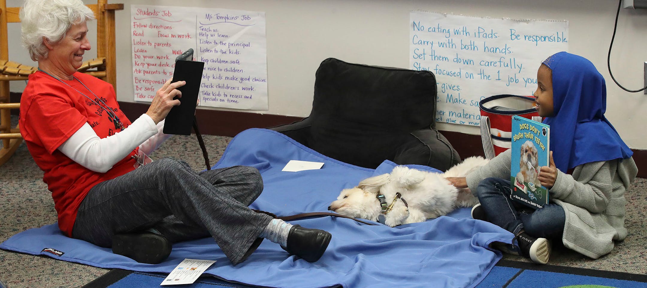 Sarah Goullaud left ,took a photo of her dog "Lily" after she was read to by Dahabo Ahmed 7, a second grader at Cedar Ridge Elementary School Monday October 30,2017 in Eden Prairie, MN.