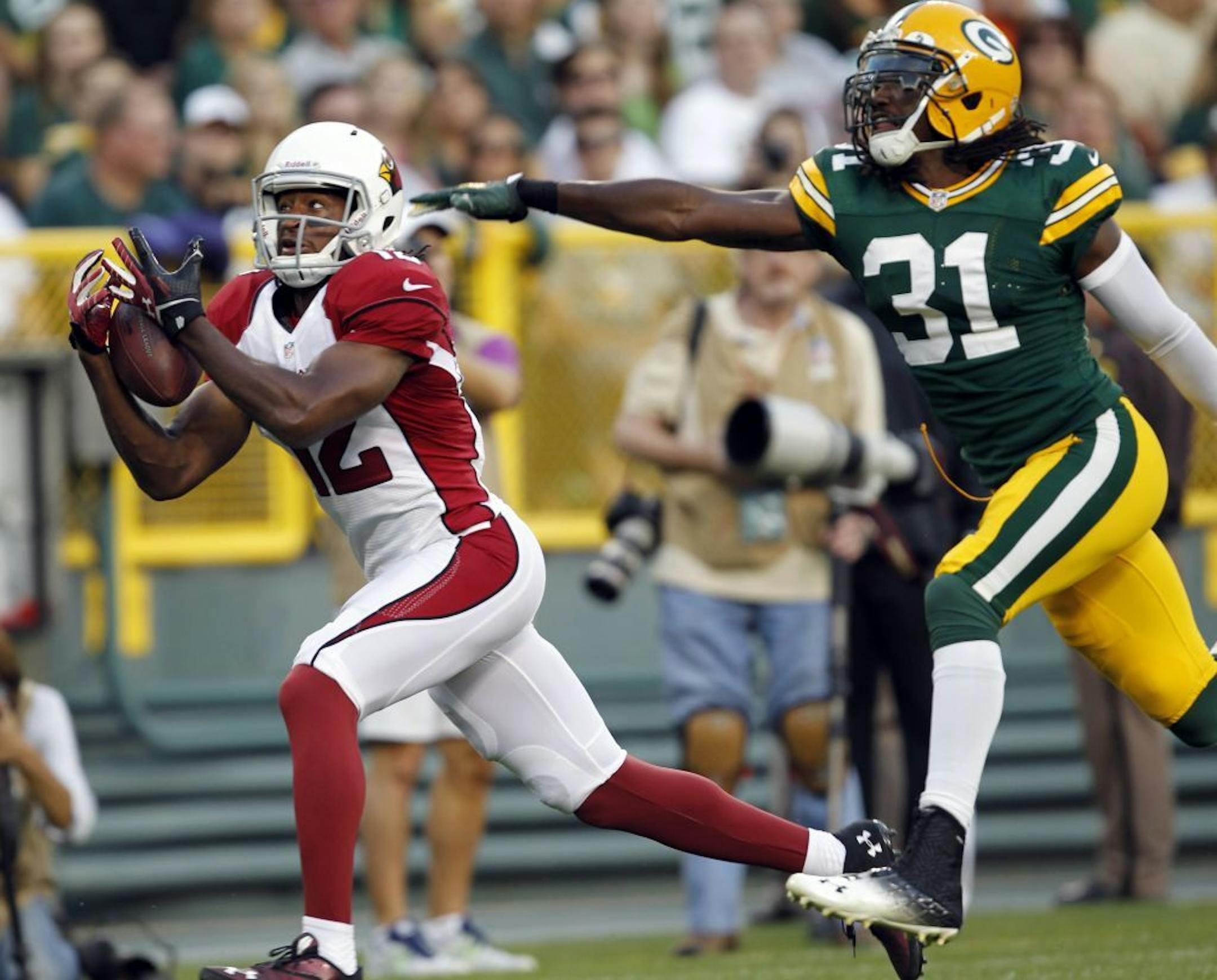 Arizona Cardinals' Andre Roberts (12) catches a touchdown pass in front of Green Bay Packers' Davon House (31) during the first half of a preseason NFL football game Friday, Aug. 9, 2013, in Green Bay, Wis.