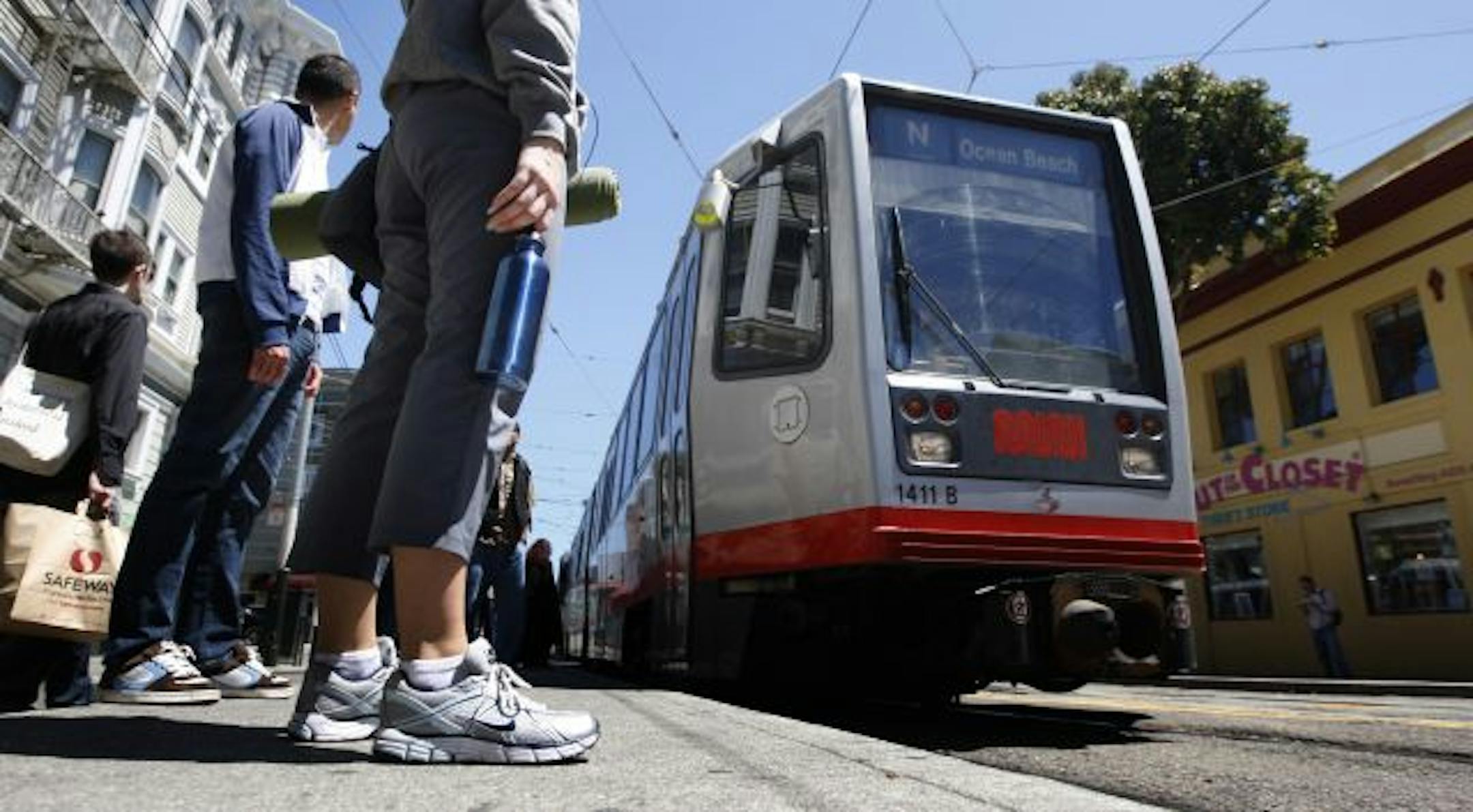 MUNI passengers wait for the light rail train on Duboce Street at Church in San Francisco.