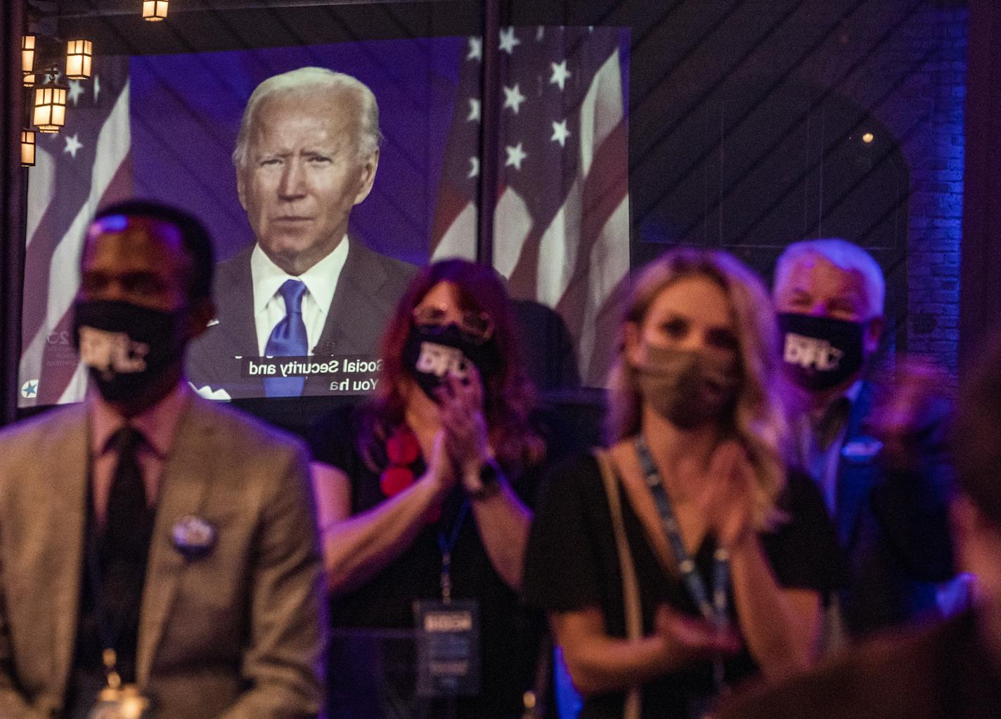 DFL supporters including Ian Oundo and Elise Eckert(blonde) listened to Joe Biden's nomination acceptance speech as he was reflected in the window from a projection at the Nicollet Island Pavillion.] DFL Party of MN hosts event celebrating the nomination of Joe Biden as the presidential candidate. RICHARD TSONG-TAATARII • richard.tsong-taatarii@startribune.com