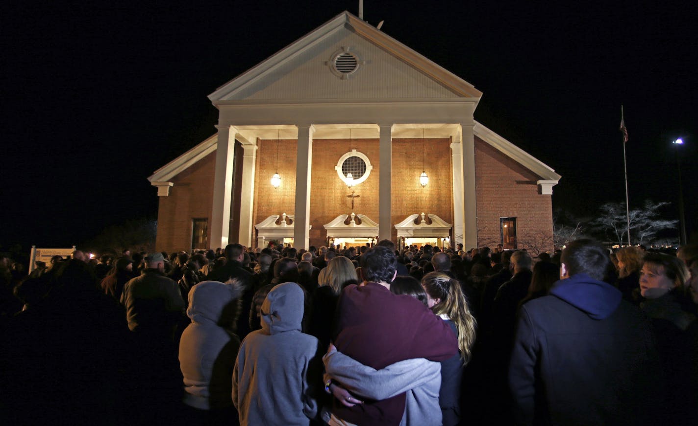 As hundreds stand outside St. Rose of Lima Roman Catholic Church, which was filled to capacity, a couple embrace during a healing service held in for victims of an elementary school shooting in Newtown, Conn., Friday, Dec. 14, 2012.