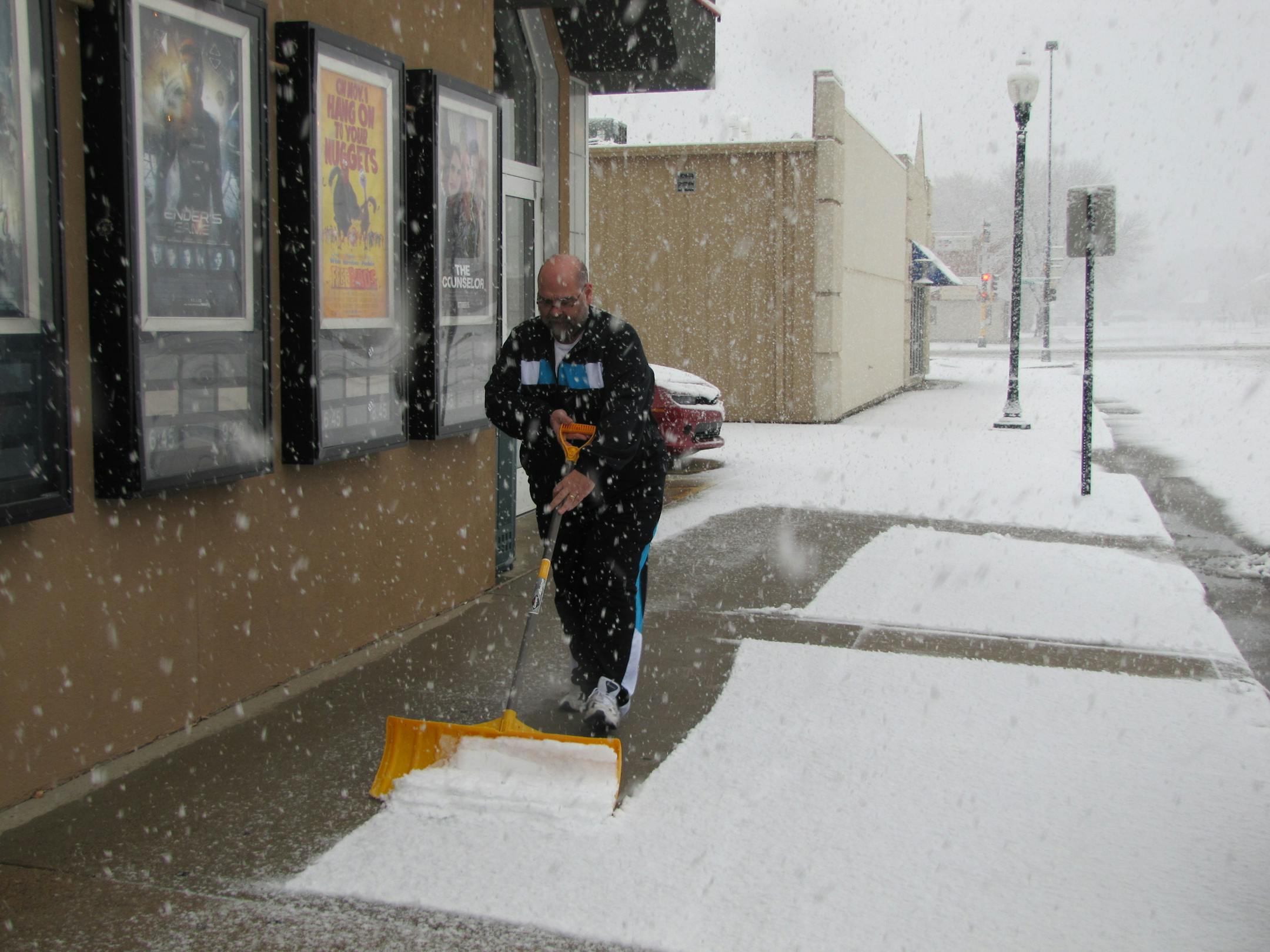 Terry Jackson, manager of Marshall 6 movie theater shovels snow Tuesday afternoon, Nov. 5, 2013, in preparation for the early show. Jackson said it was coming down faster than he could keep the sidewalk clear.