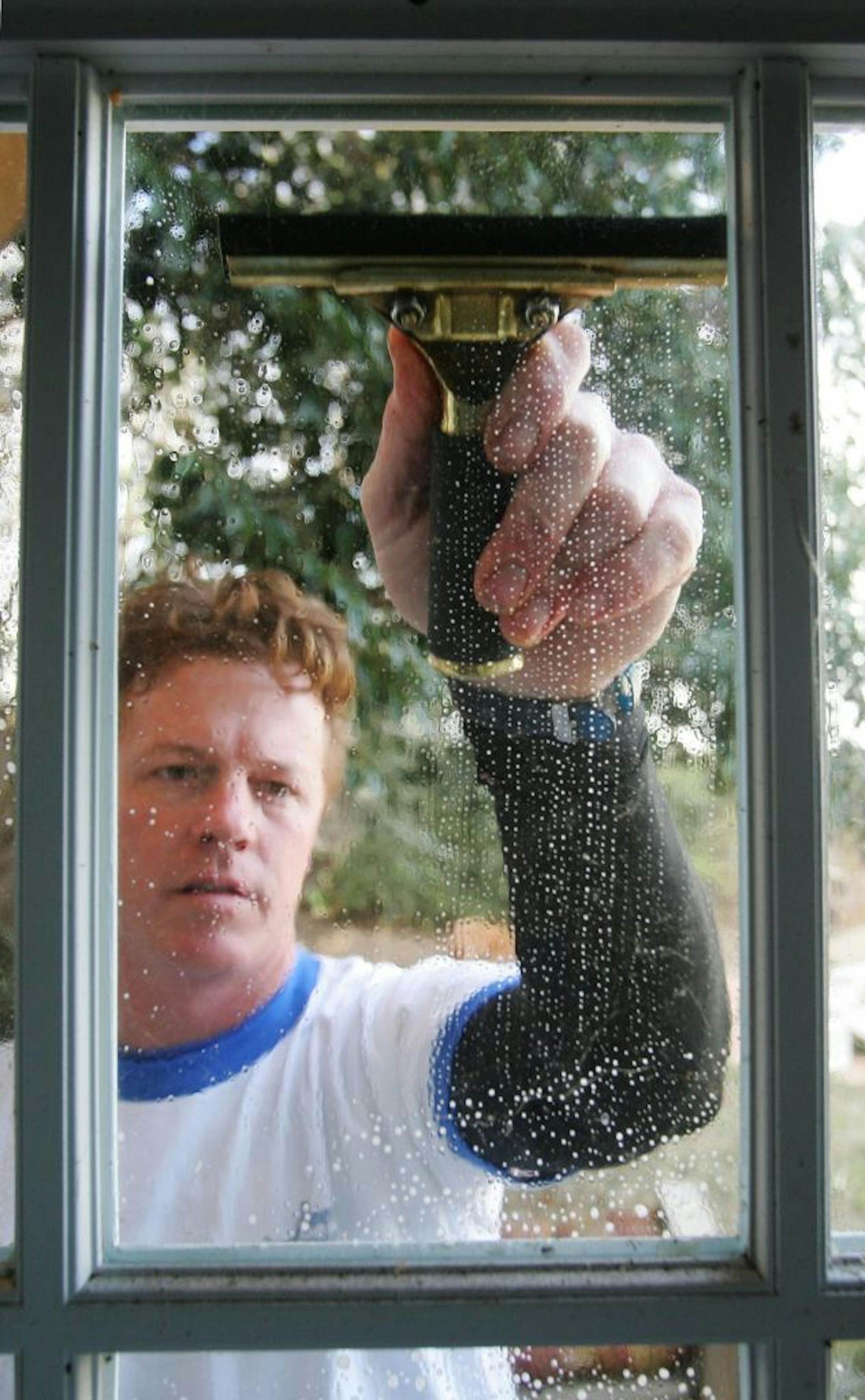 KRT LIFESTYLE STORY SLUGGED: HOME-CLEANWINDOW KRT PHOTOGRAPH BY RALPH LAUER/FORT WORTH STAR-TELEGRAM (DALLAS OUT) (January 13) Sam Burkett, of Expert Windows of Ft. Worth, Texas, uses a squeegee to wipe windows dry to prevent streaking after the windows have been washed, scraped and scrubbed. (mvw) 2005