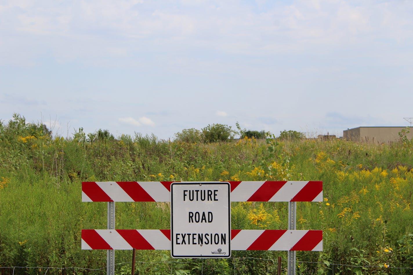 A sign indicating the location of a future road near a housing development in Woodbury.