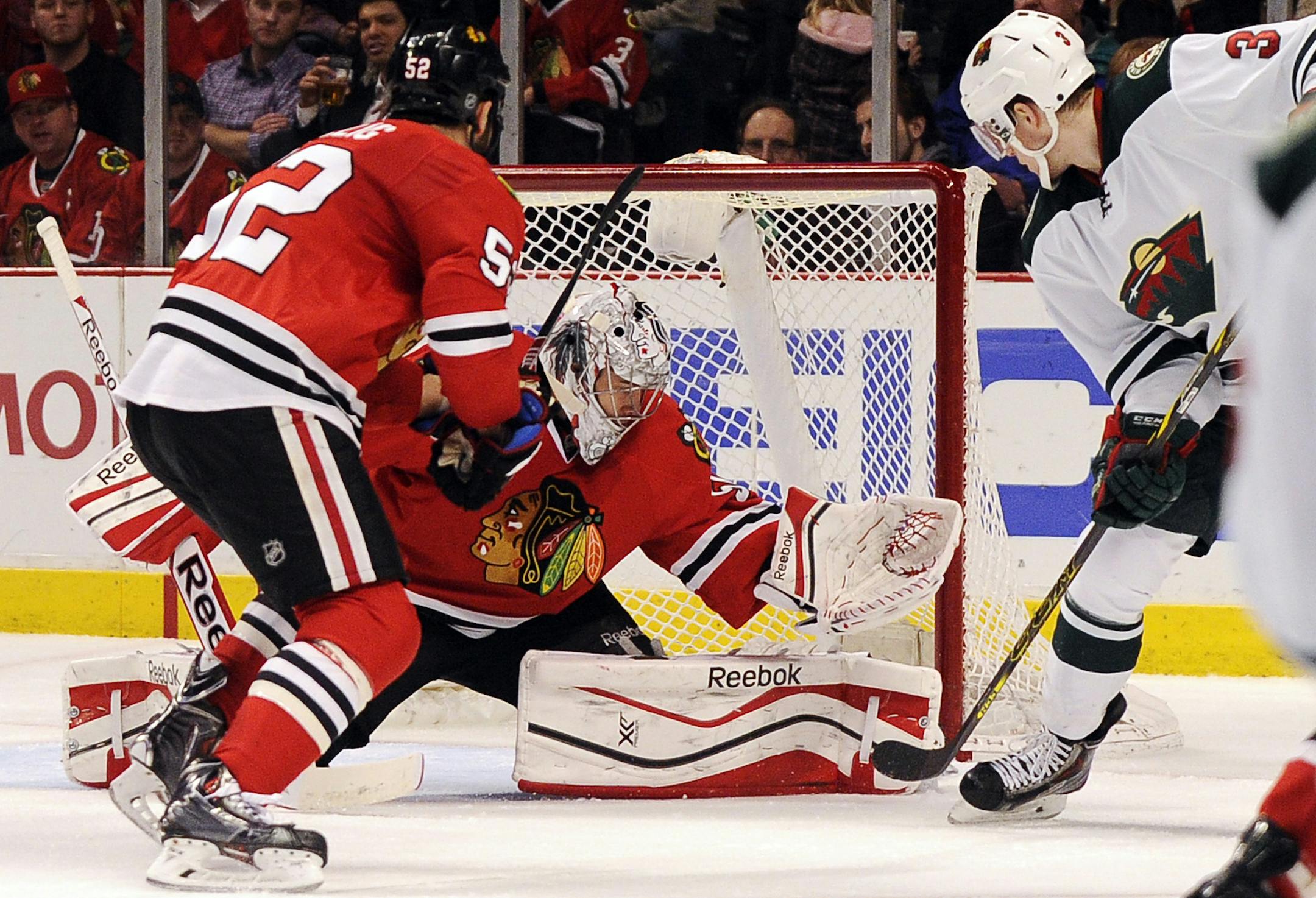 Minnesota Wild's Charlie Coyle (3) scores a goal on Chicago Blackhawks goalie Corey Crawford, center, as Brandon Bollig skates near in the first period of an NHL hockey game in Chicago, Thursday, April 3, 2014. (AP Photo/David Banks)
