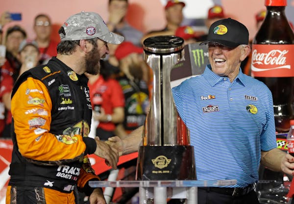 Martin Truex Jr., left, was congratulated by team owner Joe Gibbs in Victory Lane after winning the NASCAR Cup Series race at Charlotte Motor Speedway