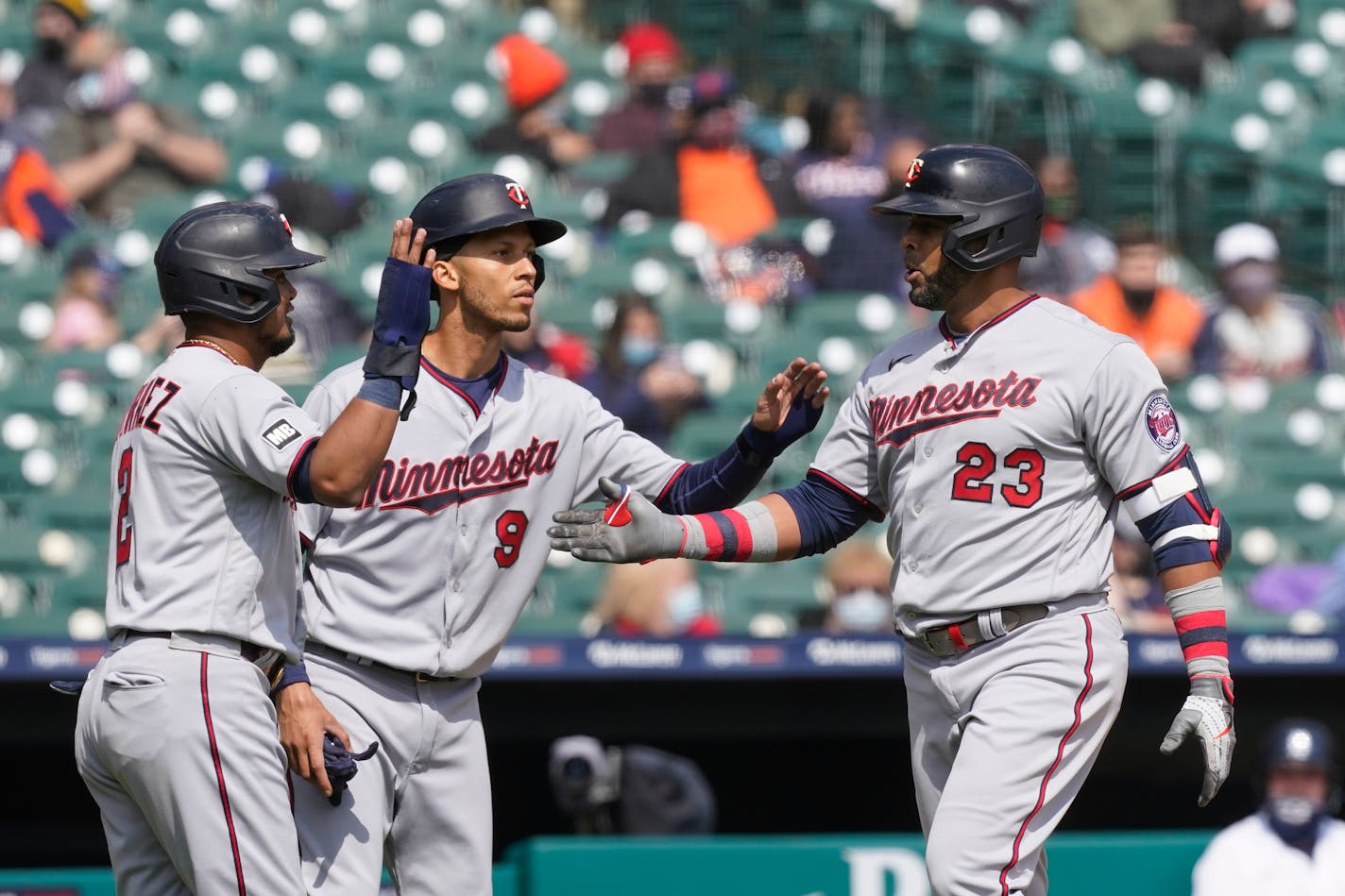 Minnesota Twins designated hitter Nelson Cruz (23) is greeted by Luis Arraez, left, and Andrelton Simmons after his grand slam during the second inning of a baseball game against the Detroit Tigers, Monday, April 5, 2021, in Detroit. (AP Photo/Carlos Osorio)