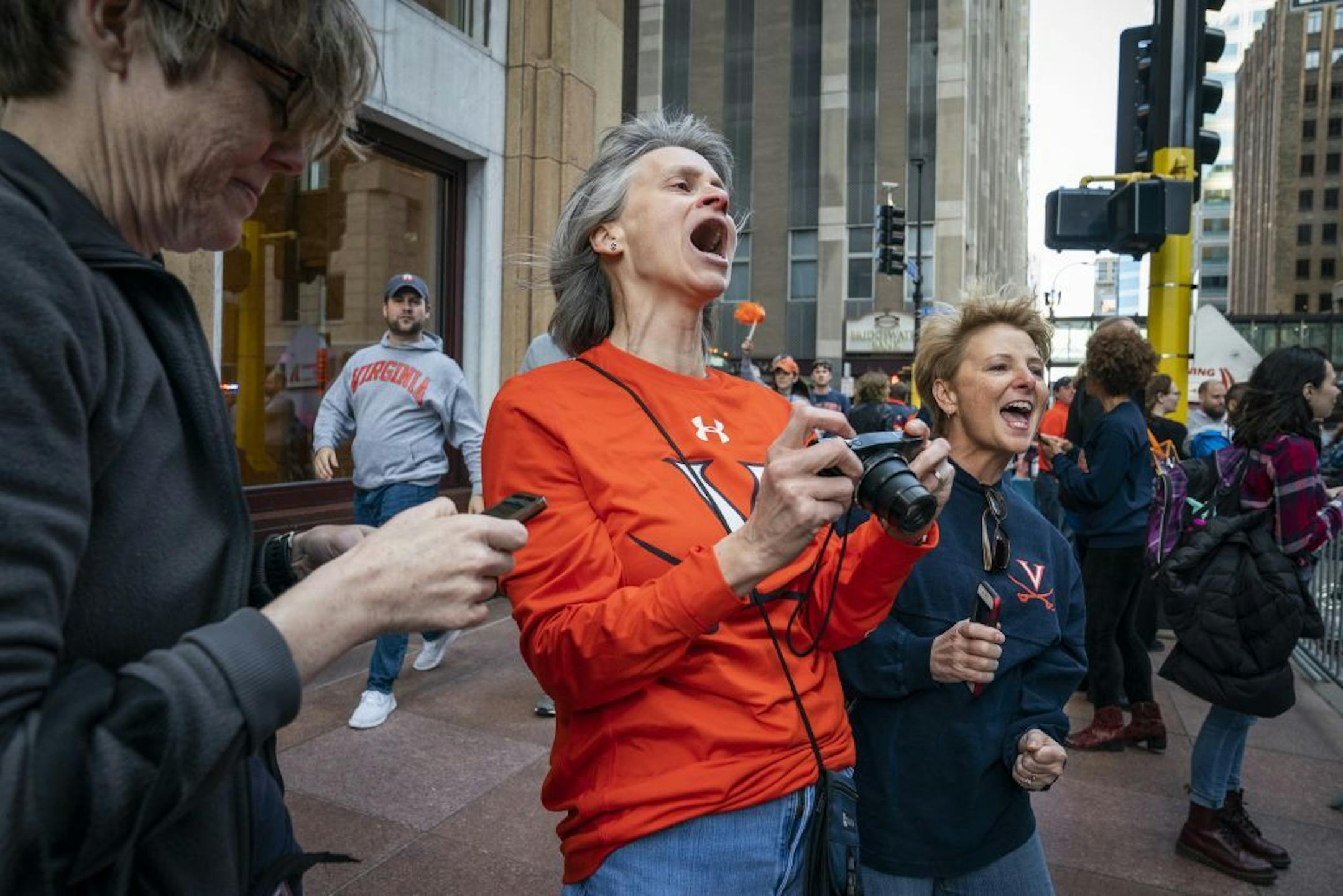 University of Virginia alumni Peggy Meehan, from left, Jennifer DiLalla and Lisa Stanfield cheer for their basketball team as they board their bus outside of the Marquette Hotel.